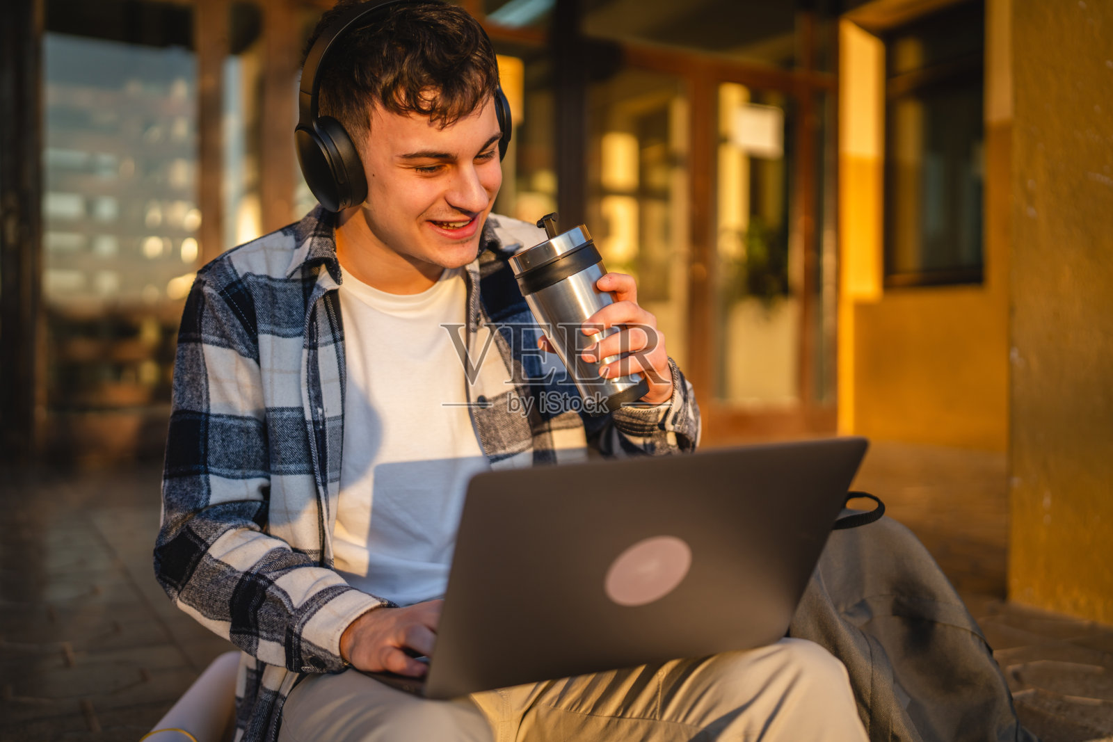 男学生坐在户外的台阶上使用笔记本电脑，为上课做准备照片摄影图片