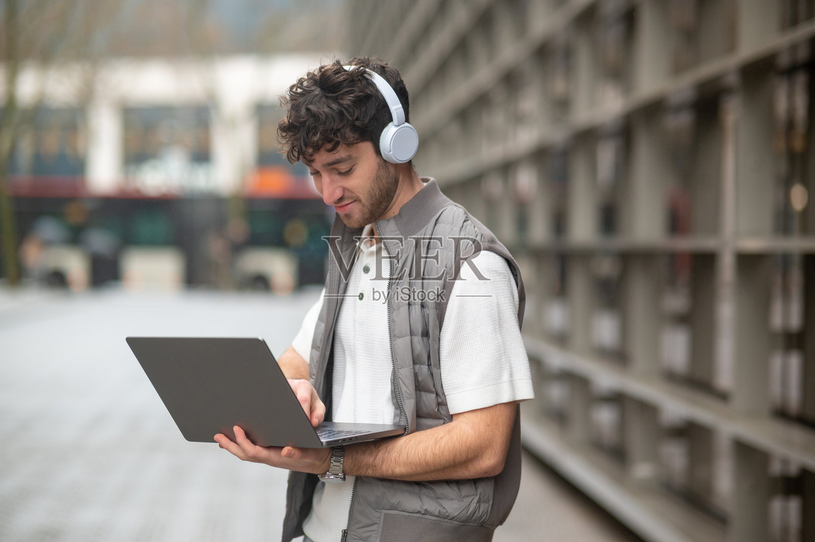 年轻男子在户外戴着耳机使用笔记本电脑远程工作照片摄影图片