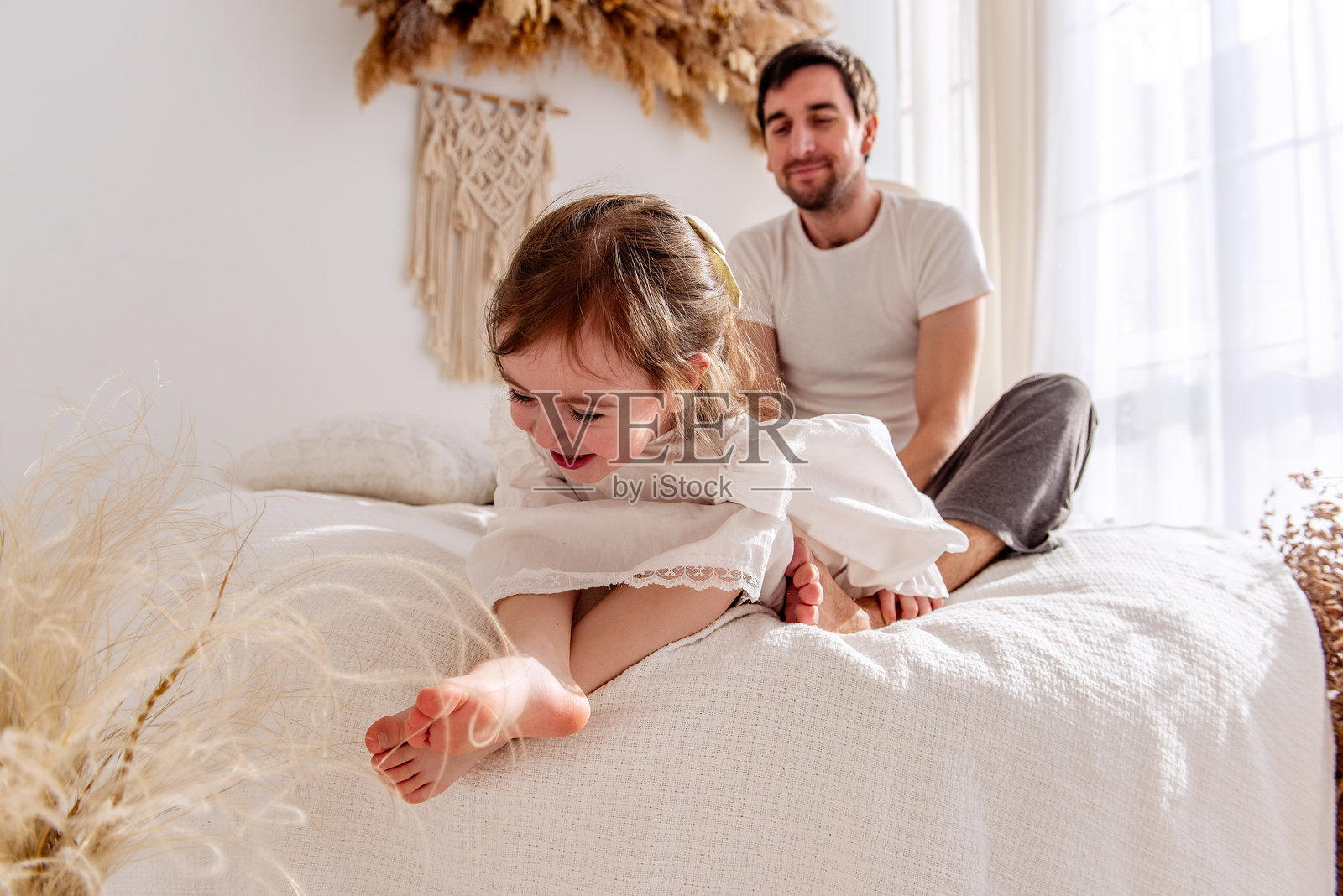 父亲在温馨的卧室里逗女儿玩耍。照片摄影图片
