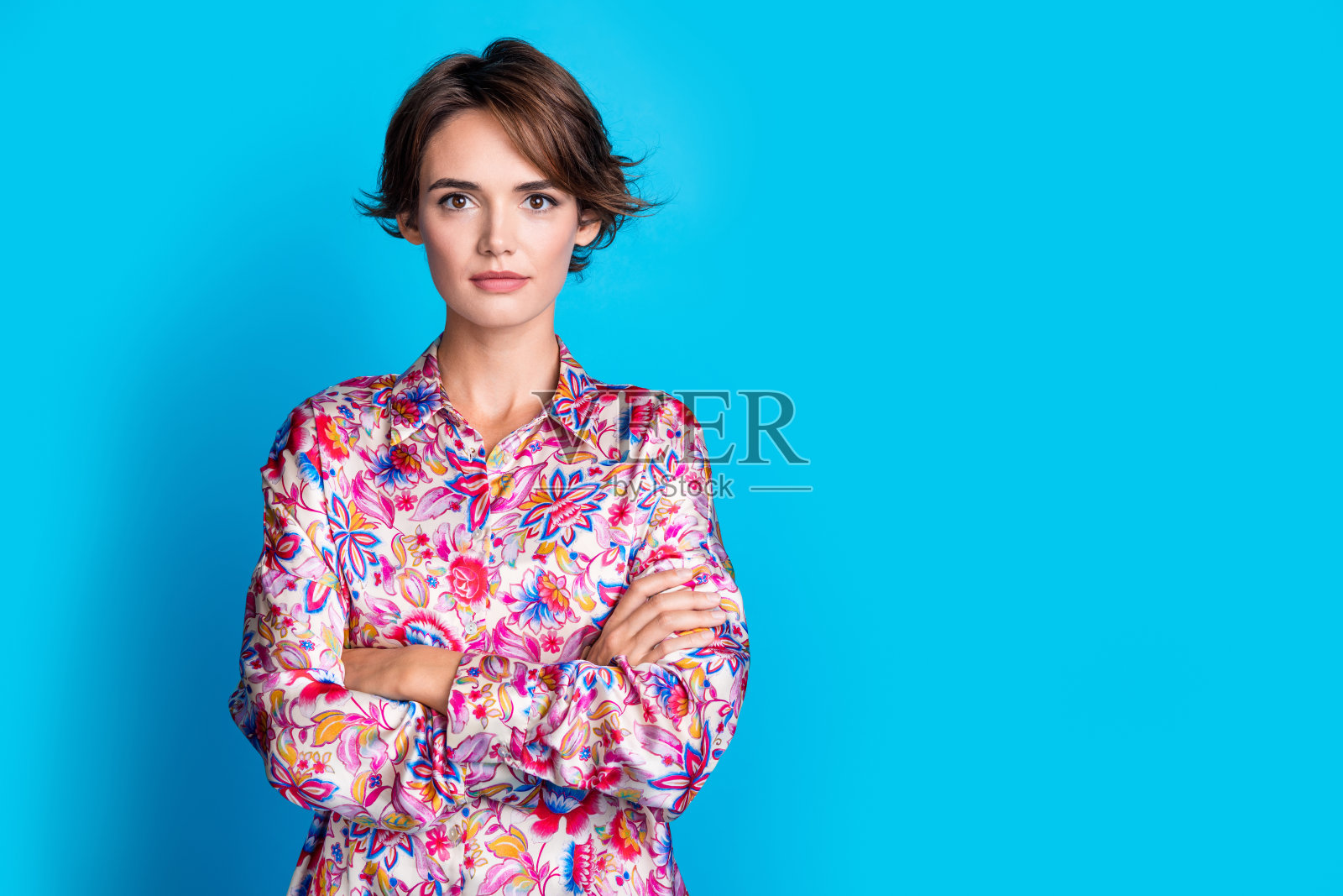 自信迷人的女孩穿着时尚服装，双臂交叉，展示空白空间，背景为蓝色。照片摄影图片