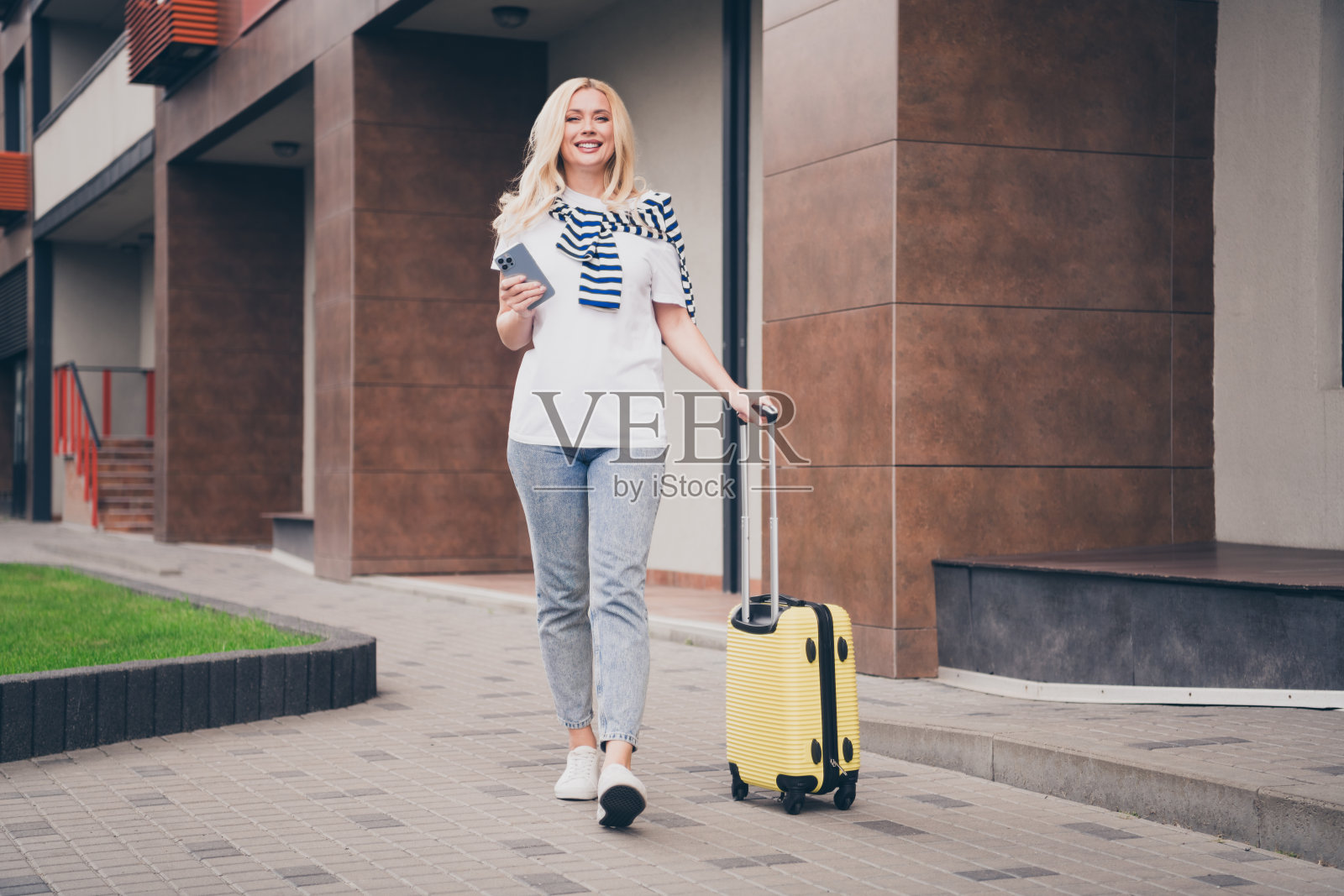 迷人的年轻女性在阳光明媚的城市中悠闲地散步，穿着休闲风格，享受旅行的乐趣照片摄影图片