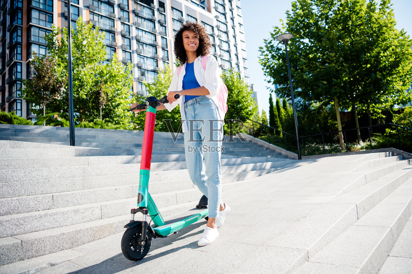 年轻女性骑着电动滑板车，在城市公园享受阳光明媚的日子，面带愉悦的微笑，穿着休闲风格。照片摄影图片