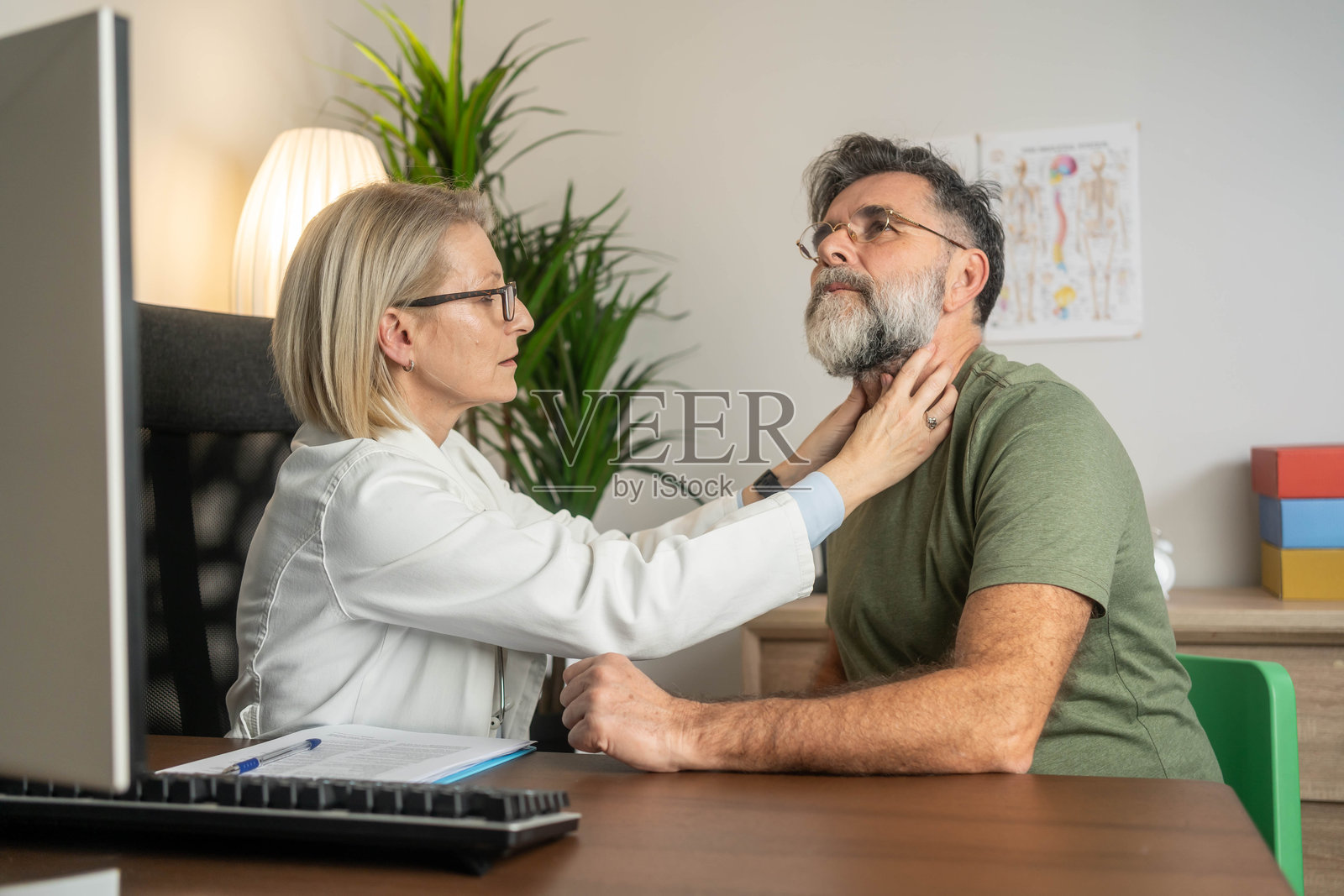女医生在咨询期间检查一位老年男性的喉咙。照片摄影图片