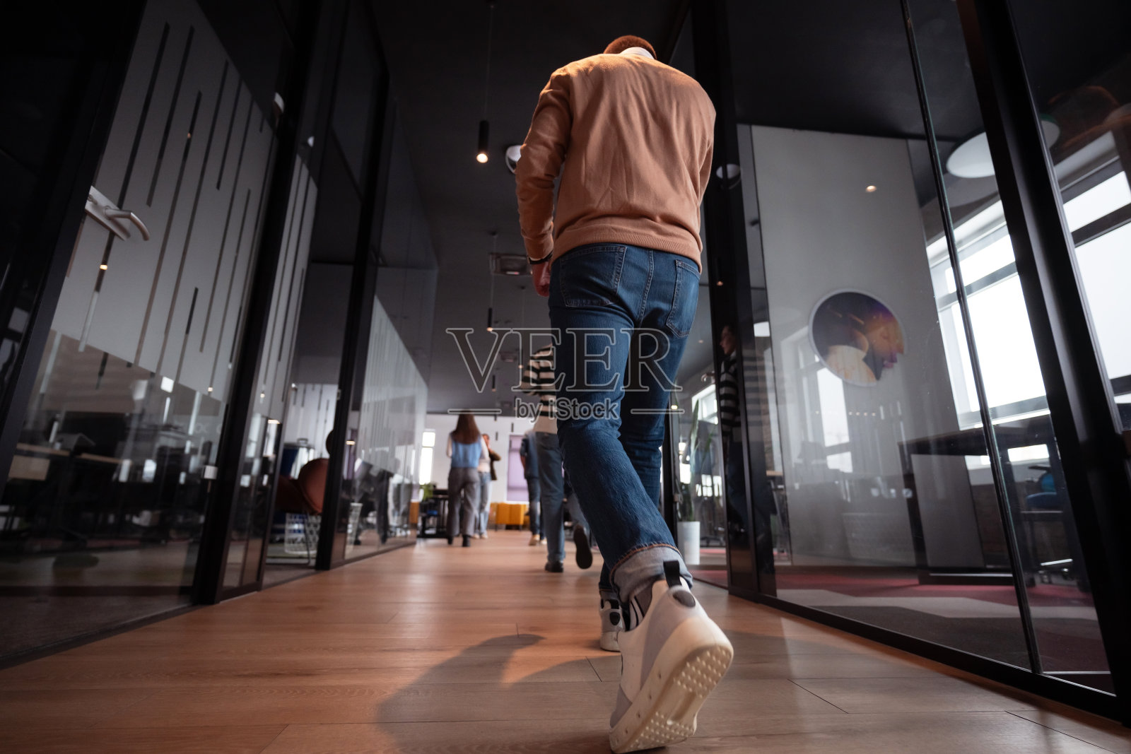 现代开放式初创公司办公室中的商务团队一起走动。多元化的商务人士在讨论时微笑。成功的跨种族同事们正在合作一个新项目。照片摄影图片