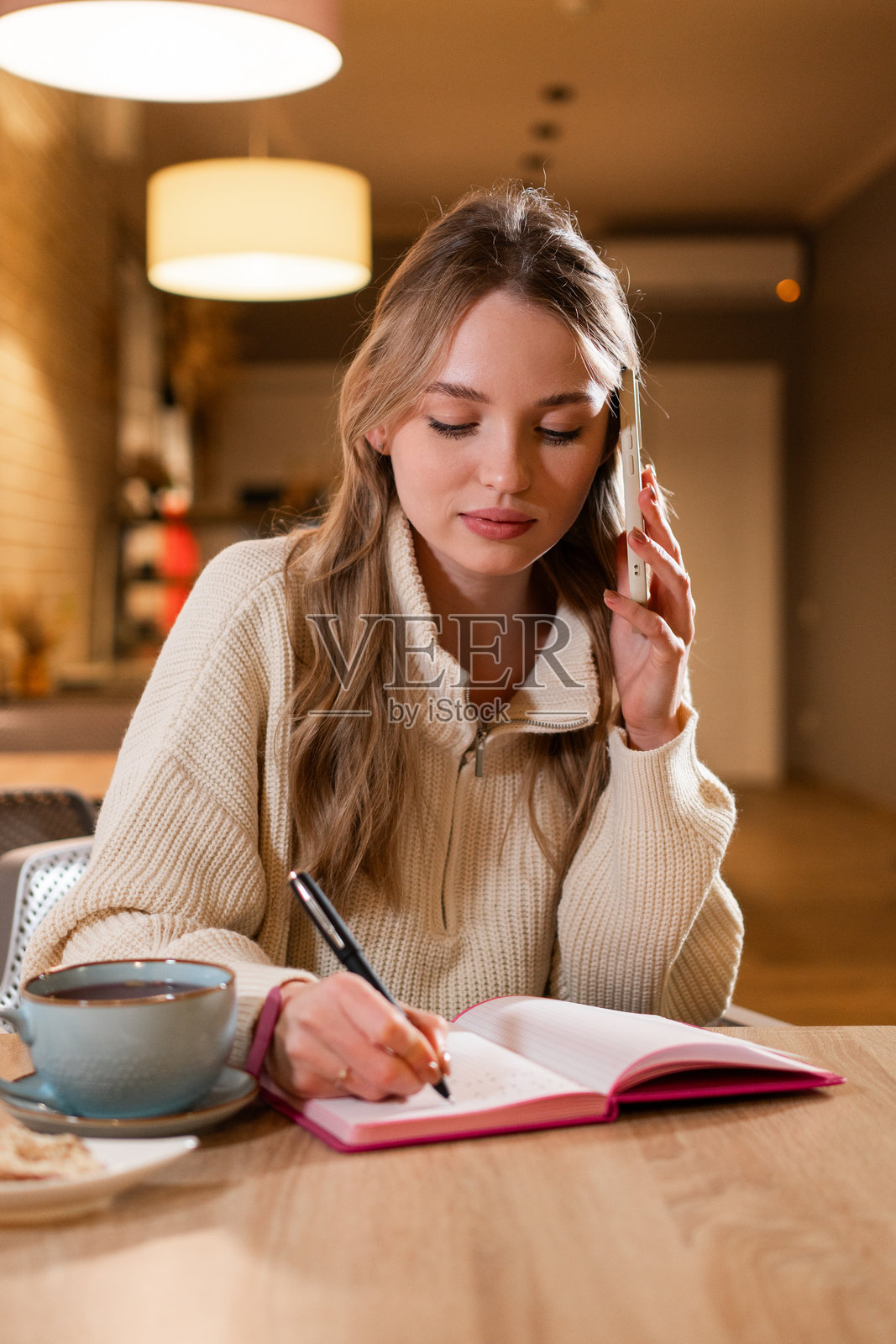女士在咖啡馆与客户通话时做笔记照片摄影图片