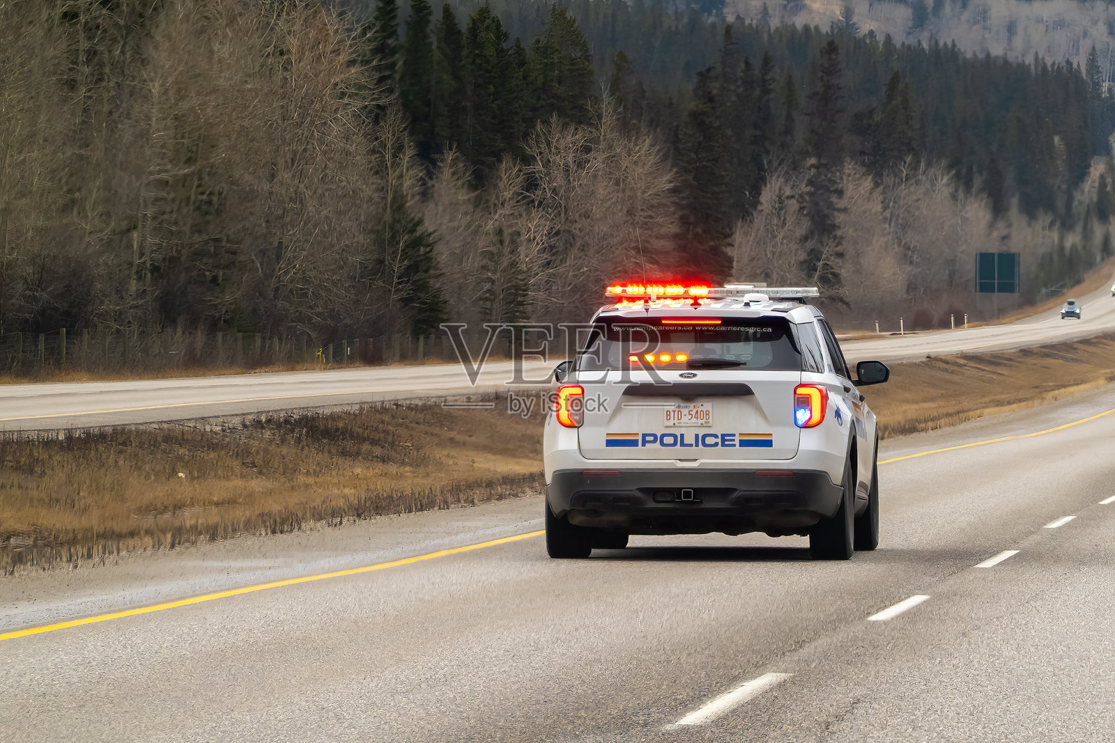 一辆闪烁灯光的警用SUV在高速公路上行驶,后面清晰可见“POLICE”字样。阴云密布的天气。照片摄影图片