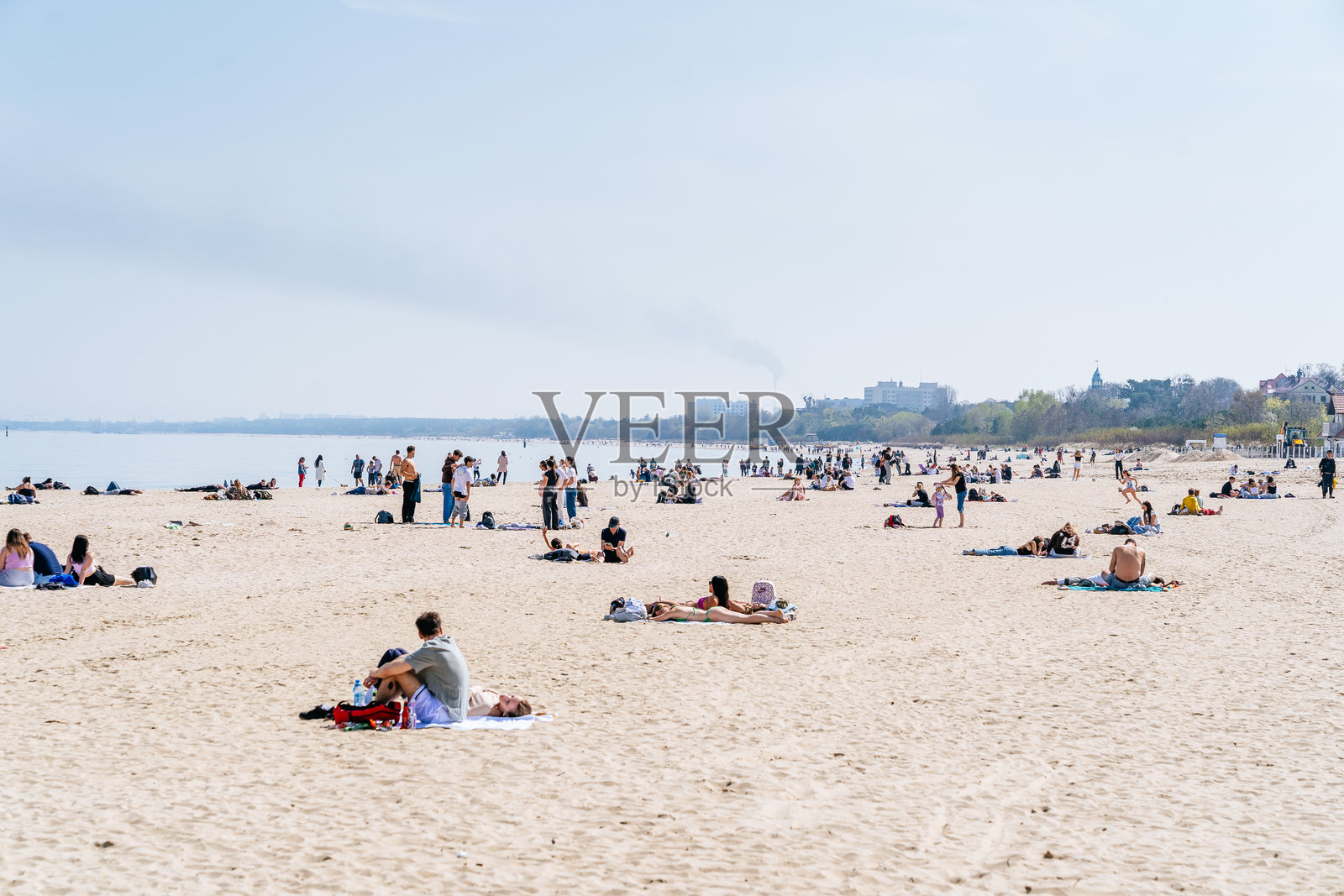 索波特海滩的宽阔视野，人们坐在沙滩上或躺在沙子上，靠近海岸线，天空晴朗。照片摄影图片