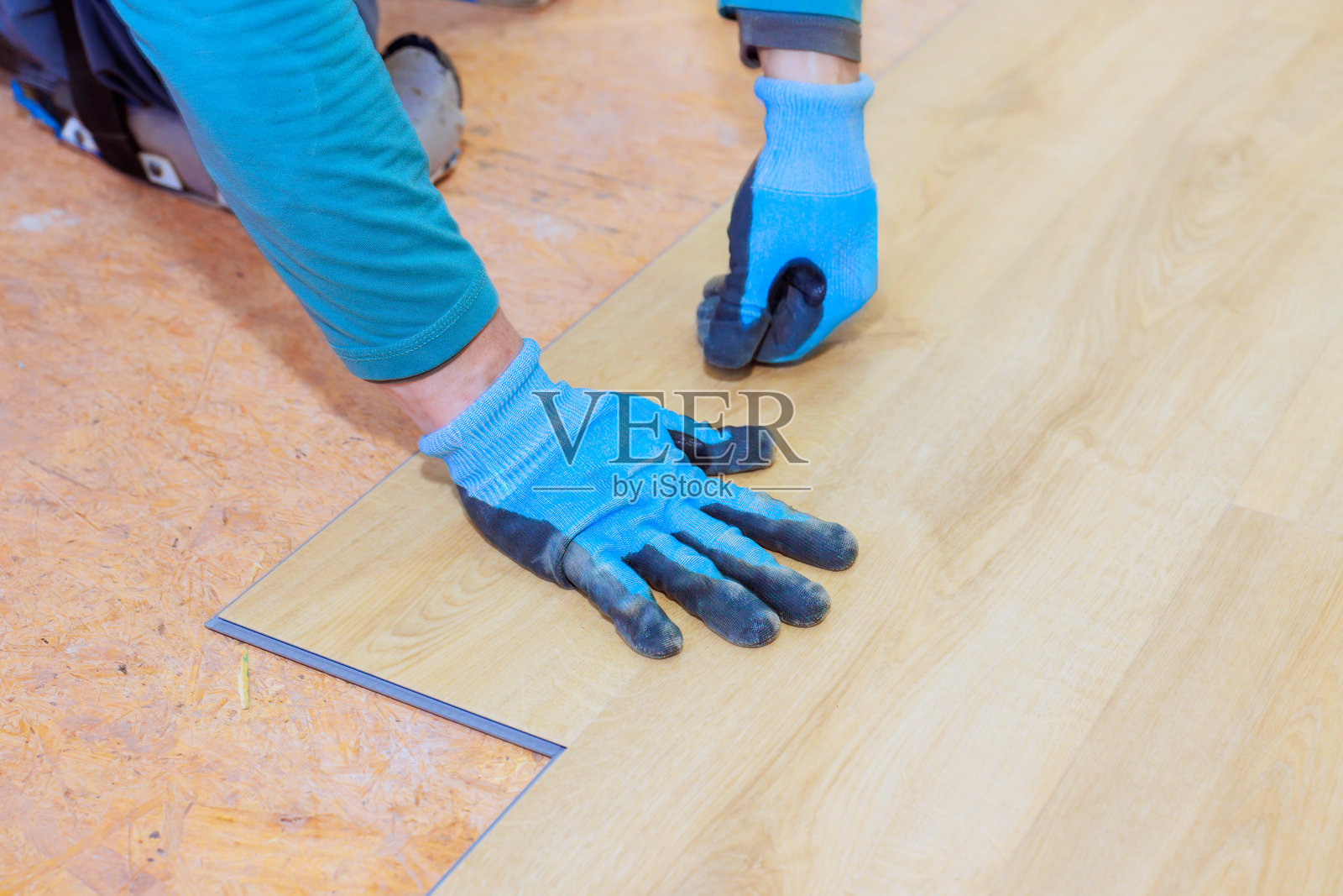 工人在明亮的室内空间进行家庭装修项目时安装复合地板照片摄影图片