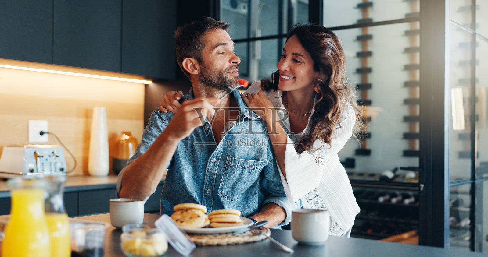 周末早晨，快乐的情侣在厨房一起享用早餐，浪漫的氛围中，夫妻共同享受健康的营养餐，增进感情，互相帮助，充满乐趣。照片摄影图片