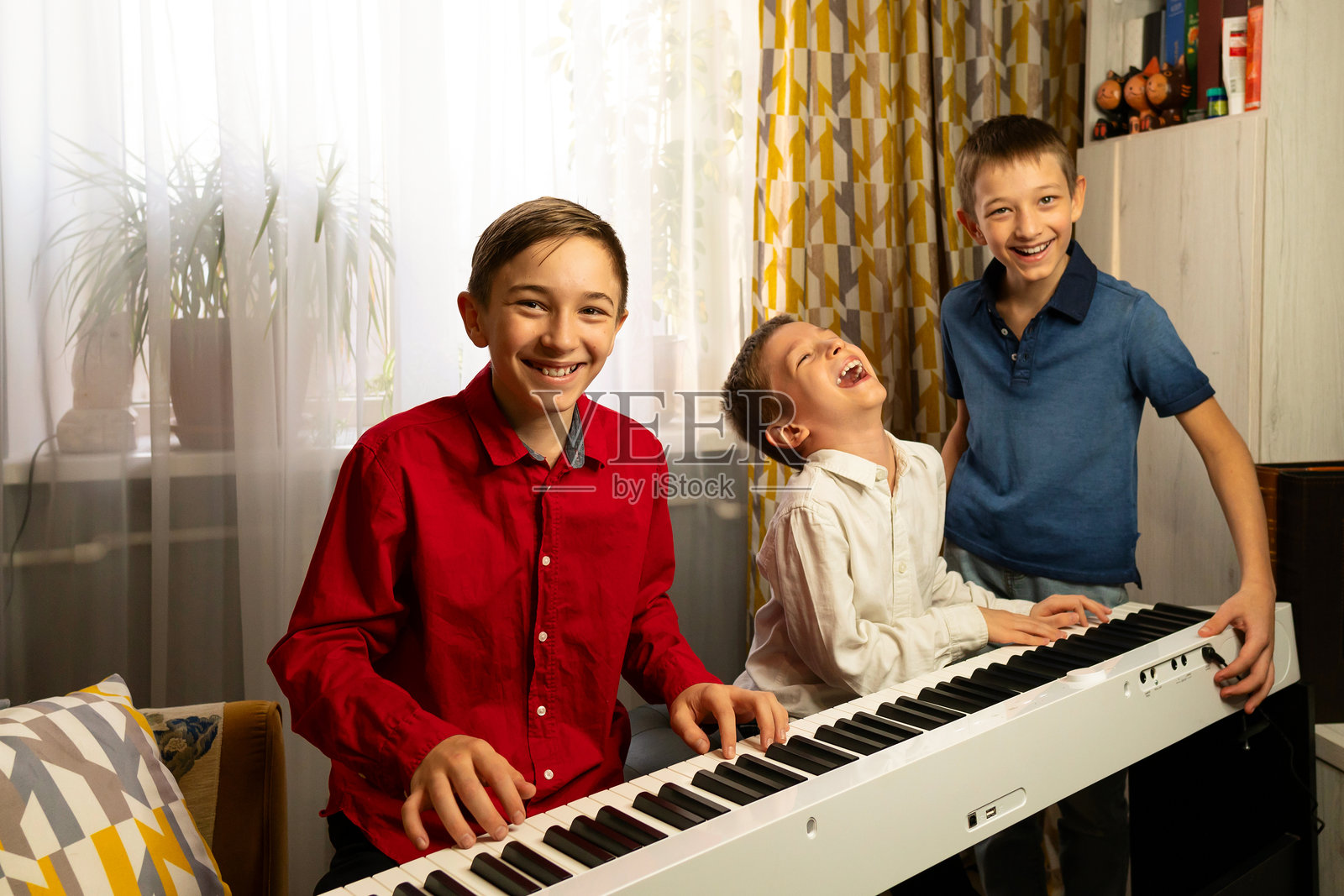 微笑的男孩们一起弹钢琴，享受音乐的乐趣照片摄影图片