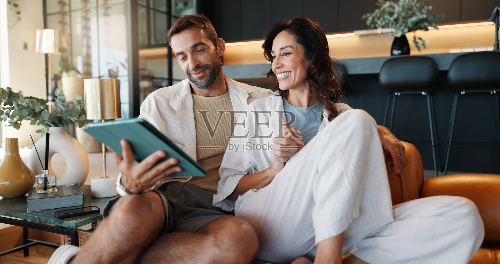 Mature couple, tablet and relax on sofa, smile and memory with streaming, video and film on web in home. People, man and woman on digital touchscreen, app and happy with movie in lounge at apartment照片摄影图片