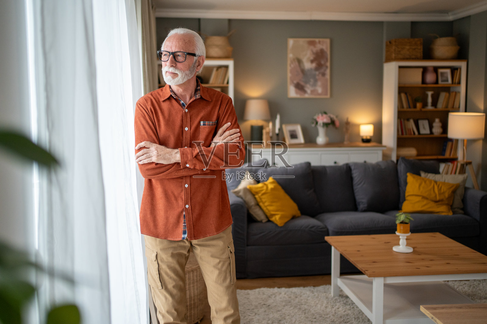 老年男子在舒适的客厅里望向窗外照片摄影图片