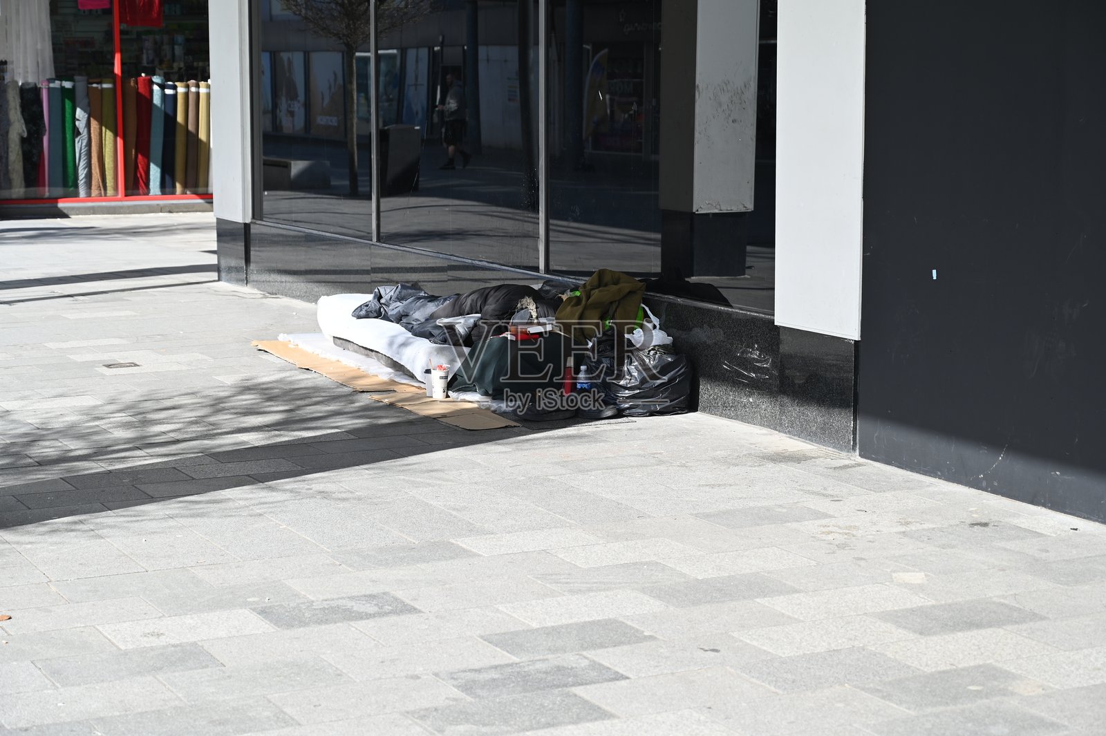 在英国西萨塞克斯郡克劳利，一名无家可归者在商店门口睡觉。照片摄影图片