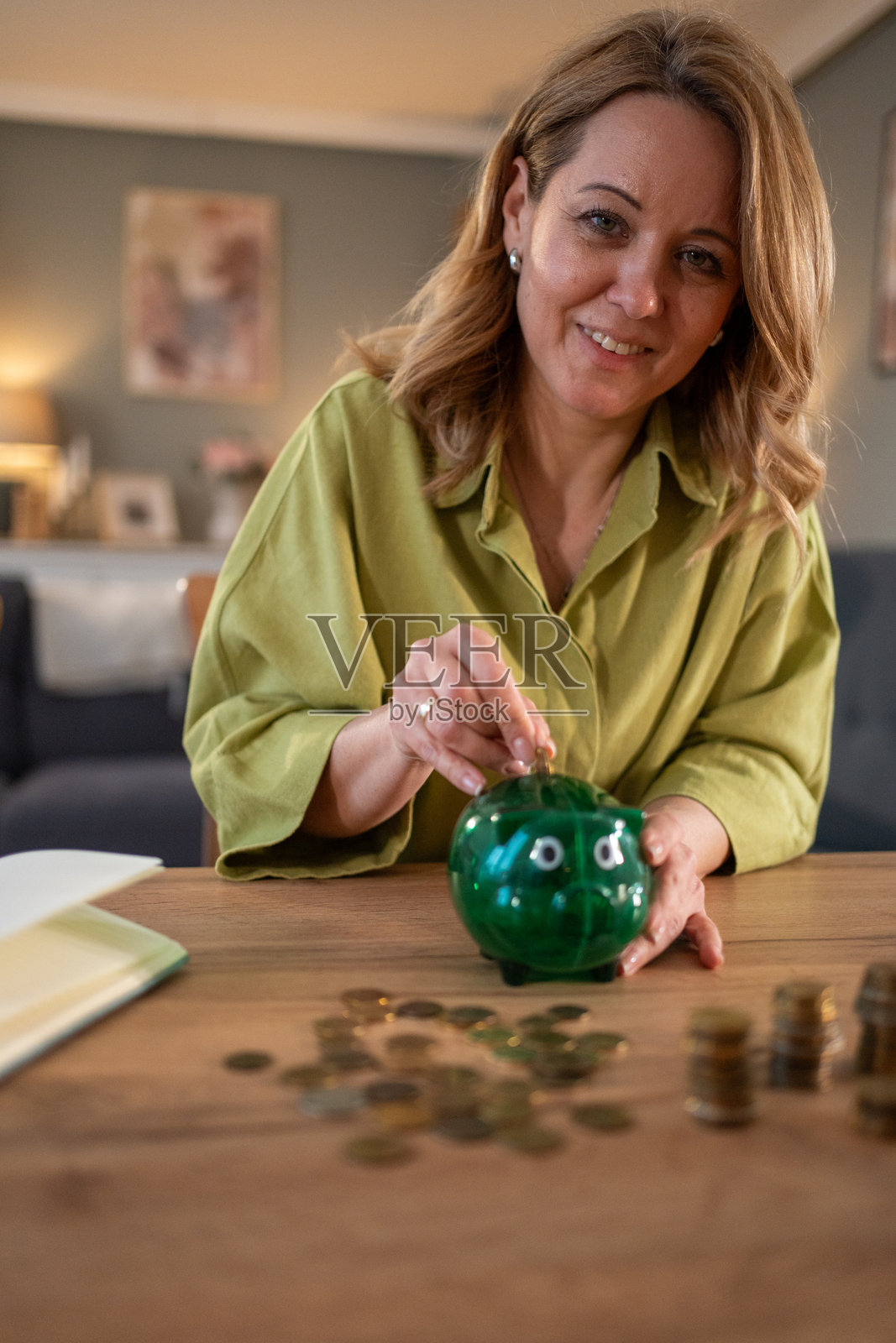 微笑的女性在家中将钱存入储蓄罐照片摄影图片