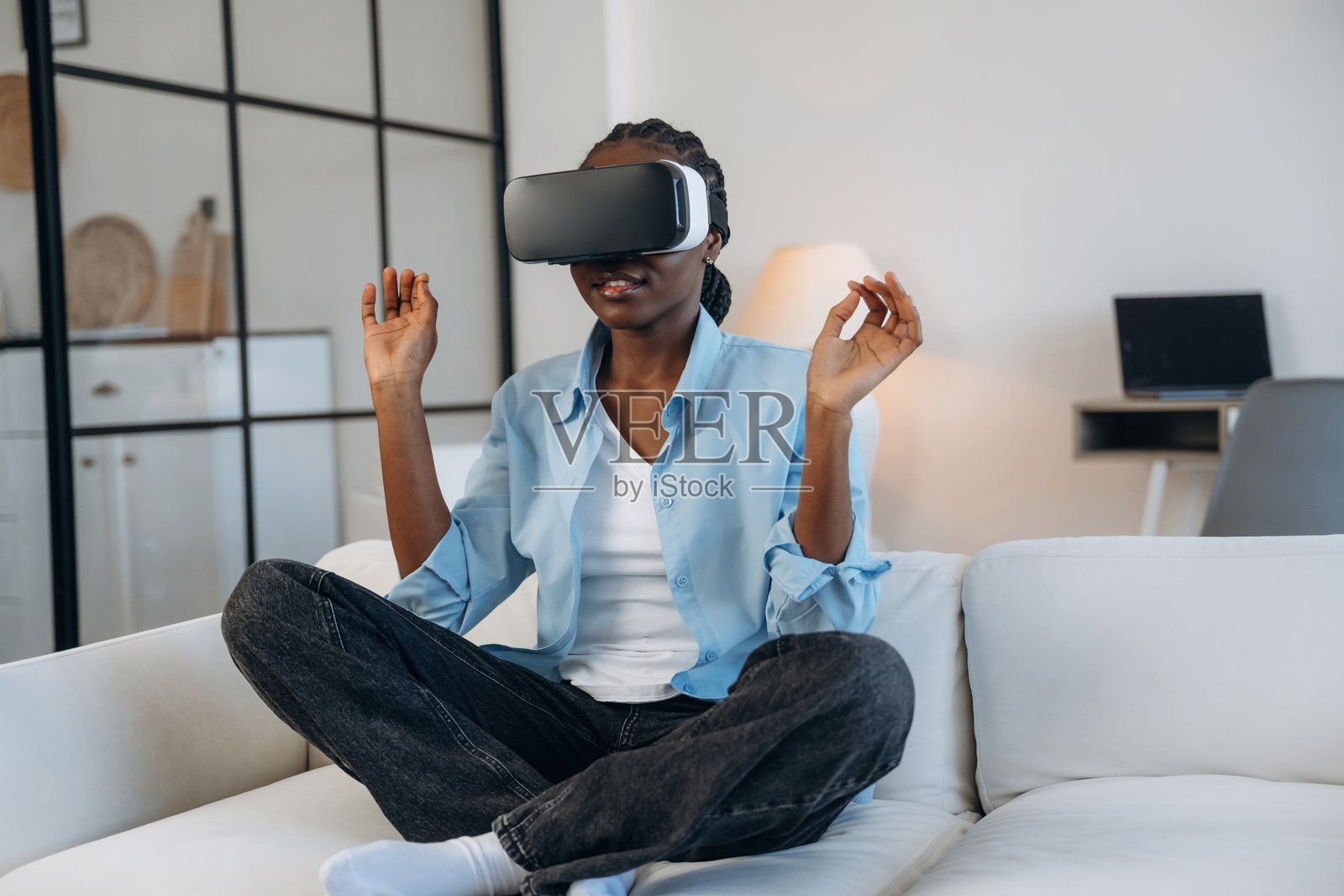 在沙发上戴着虚拟现实头盔的女人，身处家中的温馨房间。照片摄影图片