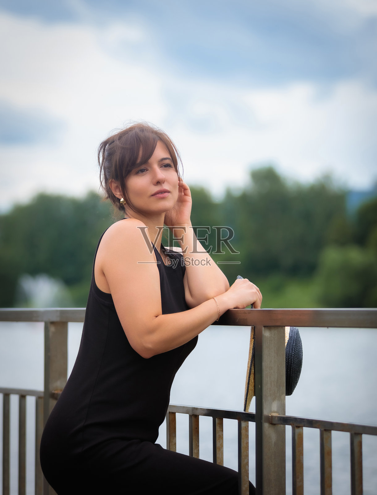 情感丰富的女人戴着帽子站在池塘边的桥上照片摄影图片