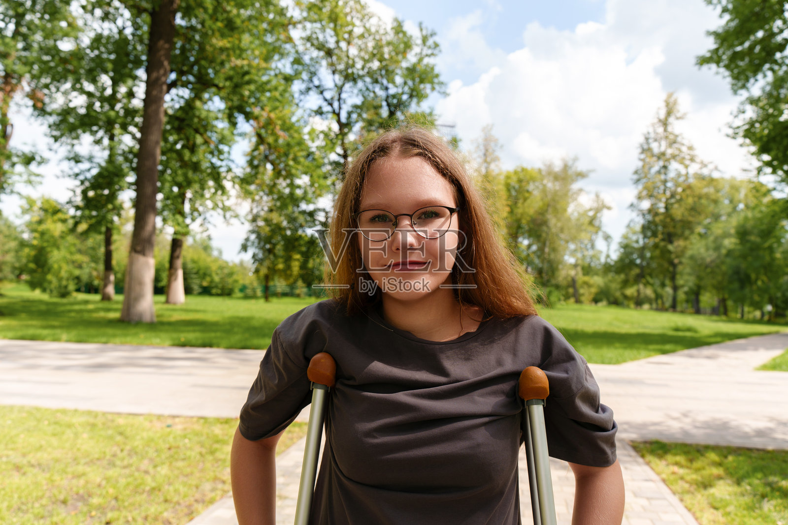 一名少女用拐杖支撑着自己，长发飘逸，专注的目光传达出她在应对行动挑战时的坚韧。照片摄影图片