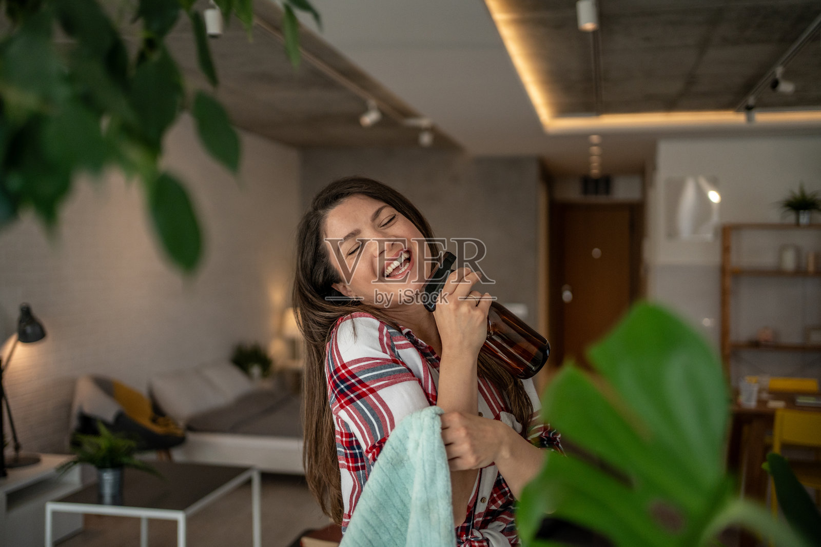 快乐的家庭主妇一边拿着清洁产品和抹布一边唱歌照片摄影图片