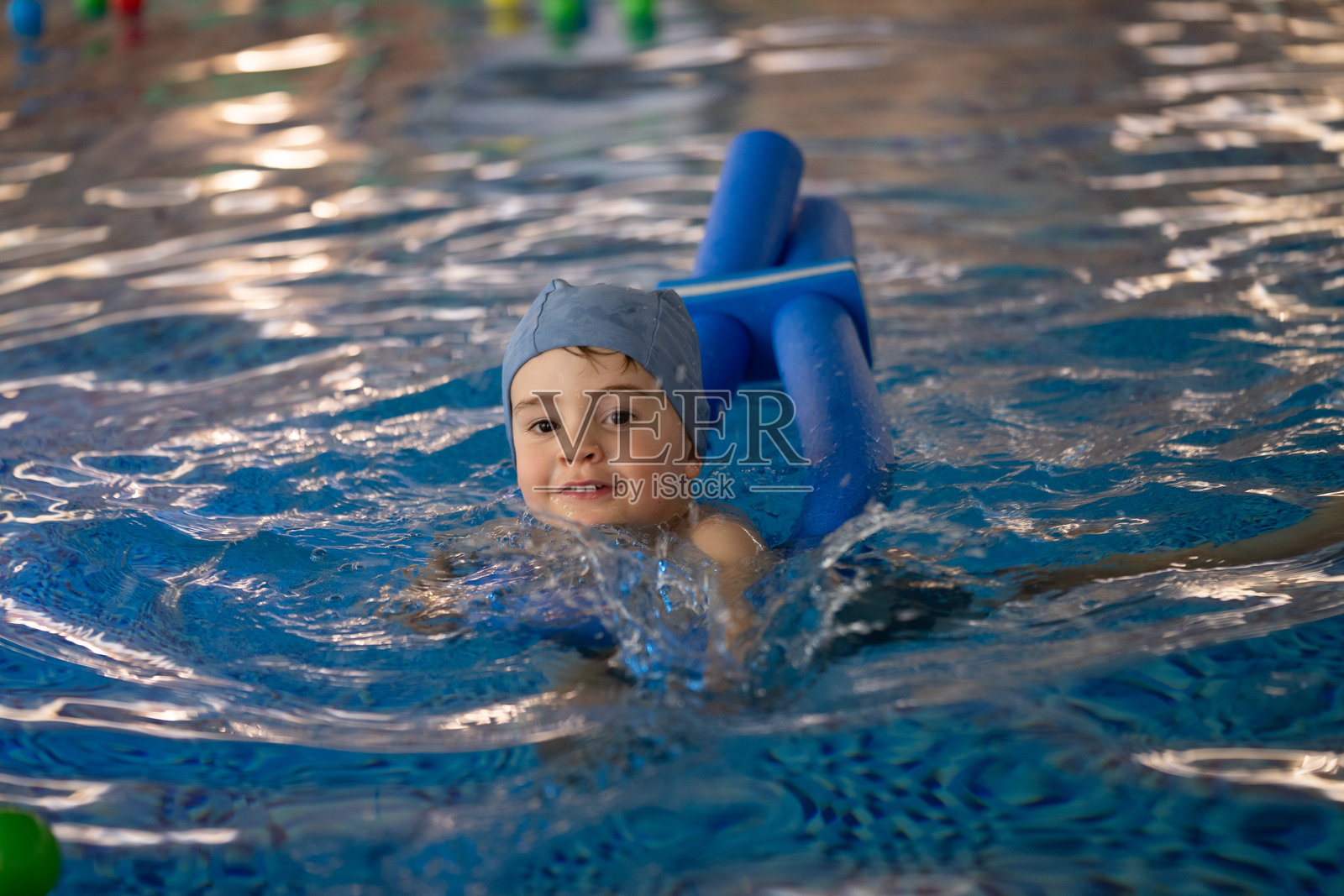 孩子在室内游泳池中使用浮具游泳照片摄影图片