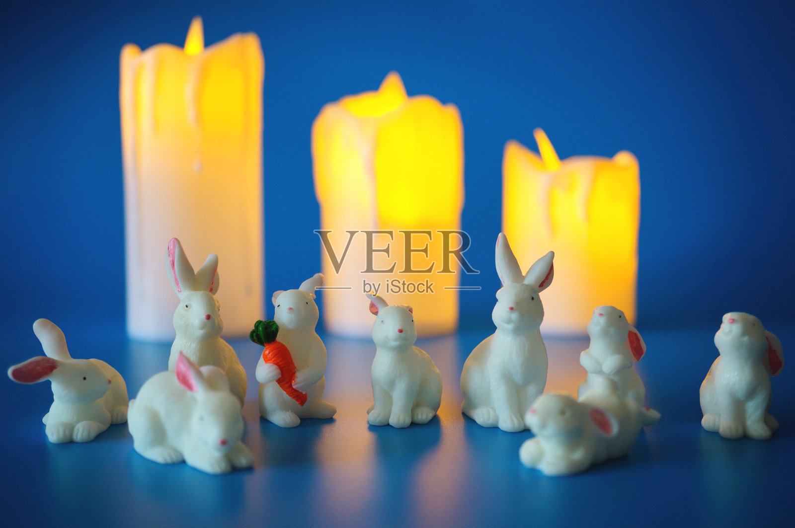 玩具白兔与燃烧蜡烛的背景。照片摄影图片