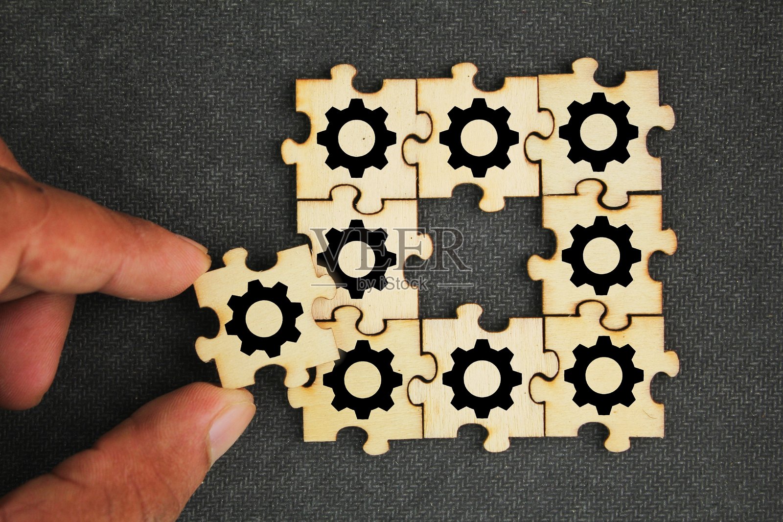 带齿轮图标的拼图，管理解决方案标志。代表团队合作、问题解决和系统集成。一只手握着一块拼图，象征着组装过程中的最后一步。照片摄影图片