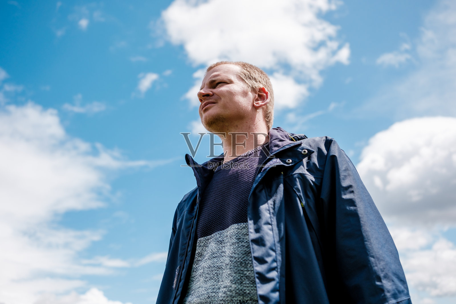 年轻男子仰望多云的天空，脸上带着希望的表情照片摄影图片