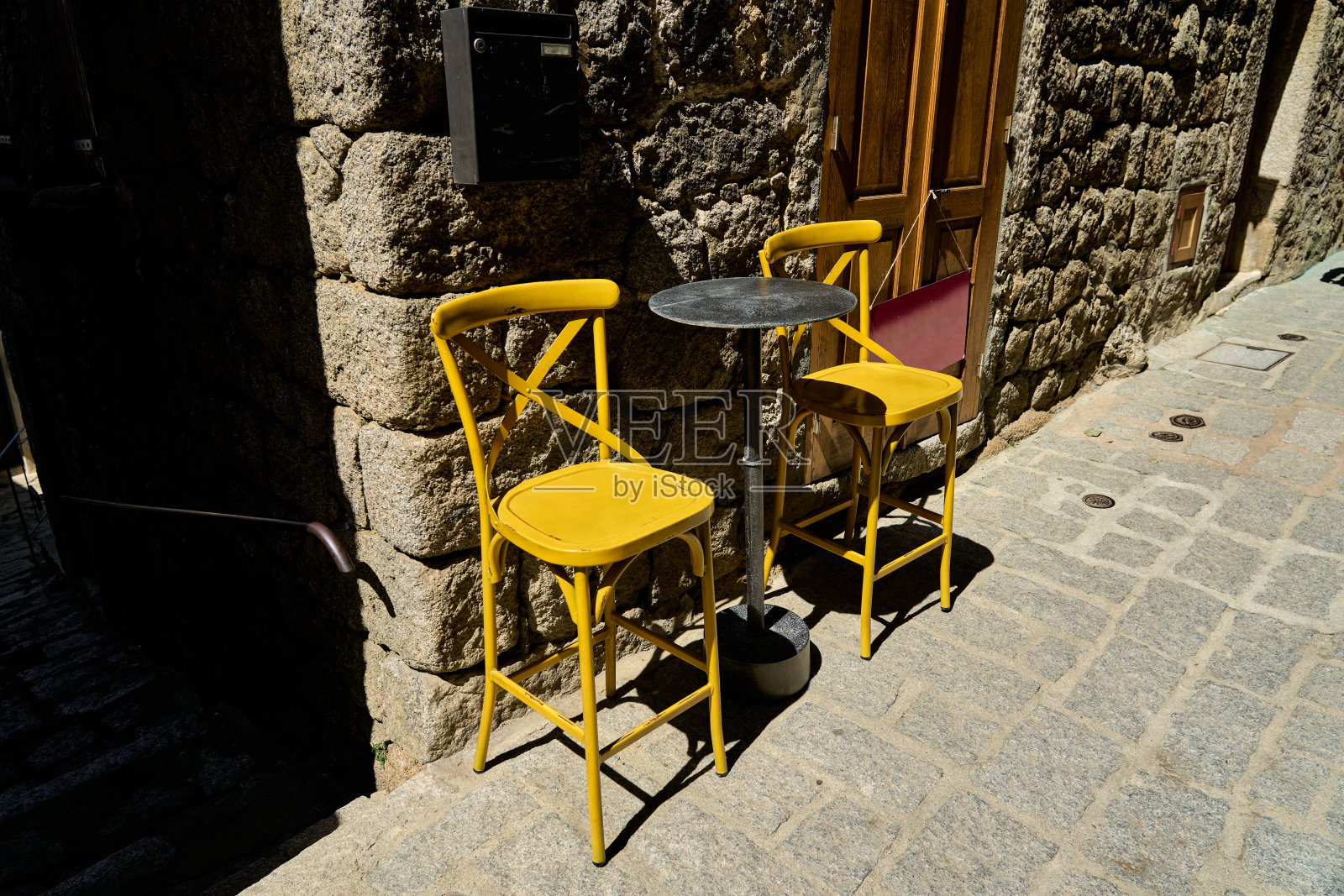 萨尔滕一条狭窄小巷中的两把黄色餐椅和一张圆桌照片摄影图片