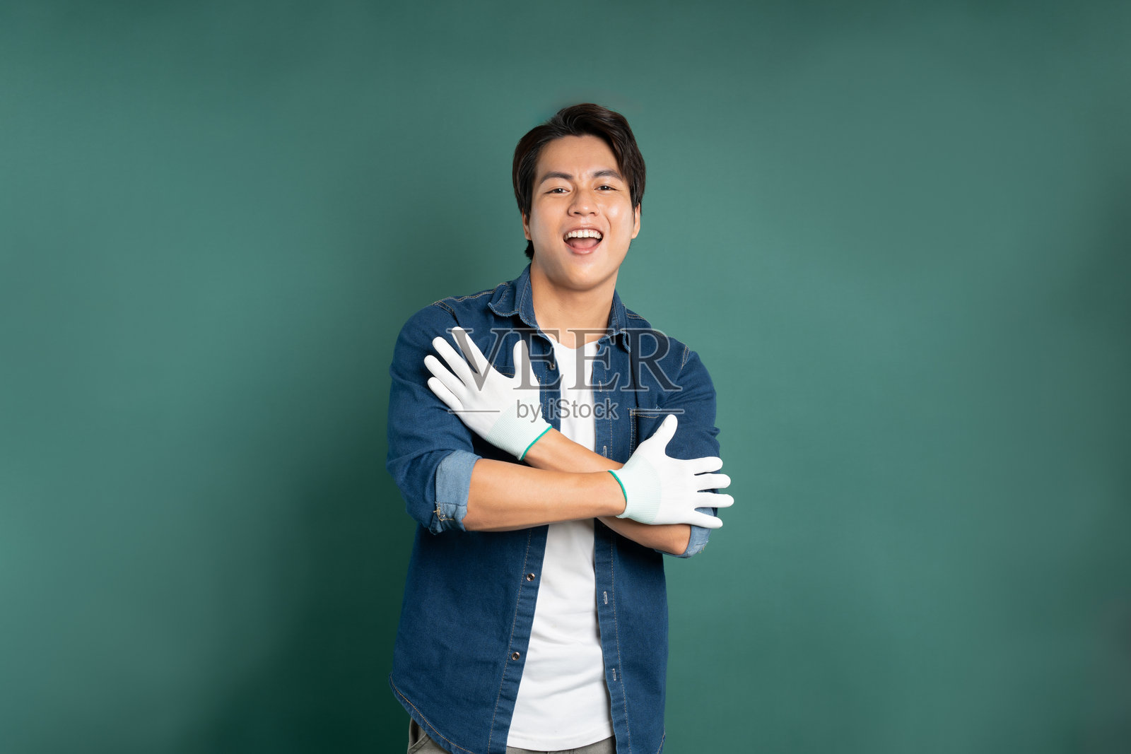 一位亚洲男性画家在绿色背景前摆姿势的肖像。照片摄影图片