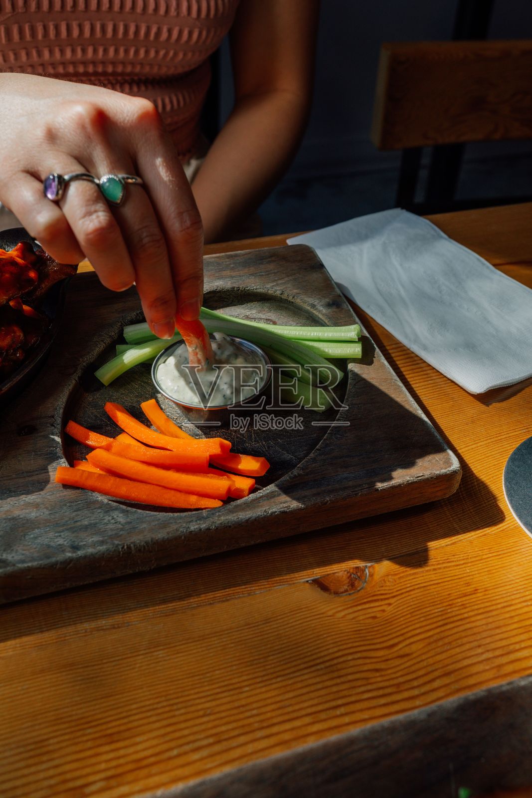 女人在餐厅里将胡萝卜蘸入牧场酱中照片摄影图片