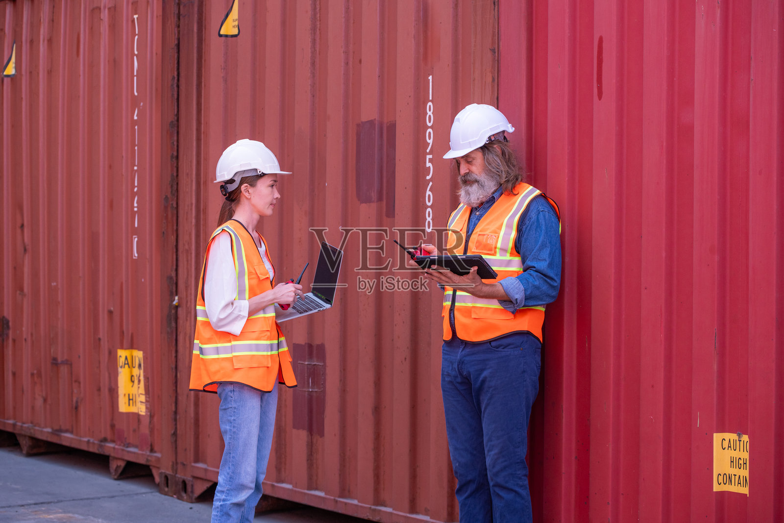 码头工人或工程师监督操作物流和货运场地，管理库存、发货时间表或集装箱追踪技术，以及航运行业的安全，描绘一位在集装箱场地工作的专业人士。照片摄影图片