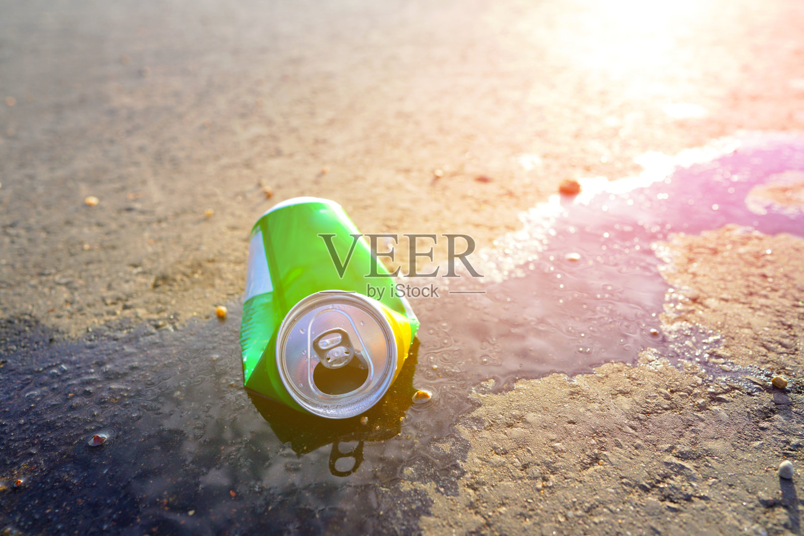 破损的汽水罐在沥青路面上，饮料洒落一地。照片摄影图片