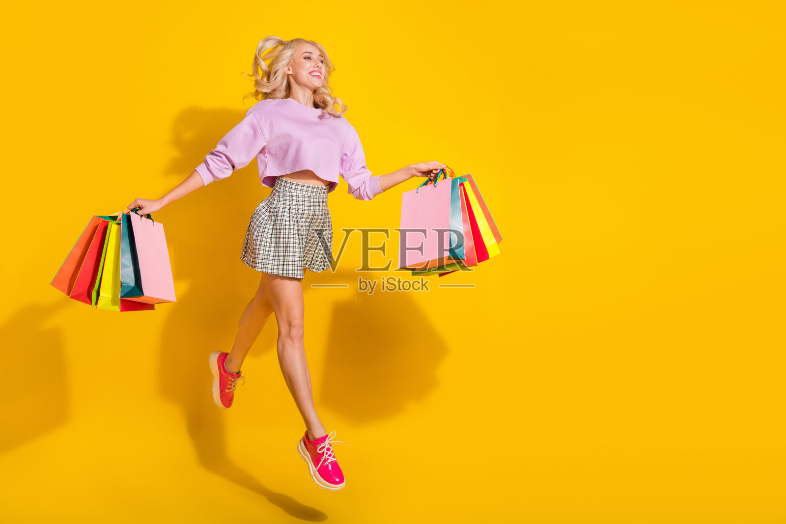 全身肖像，活力四射的人在黄色背景下空旷的空间中手持包裹。照片摄影图片