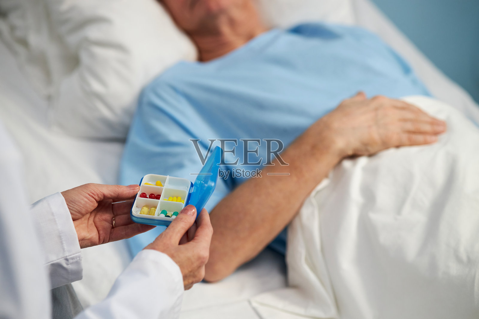 医生在住院病人旁边拿着药盒照片摄影图片