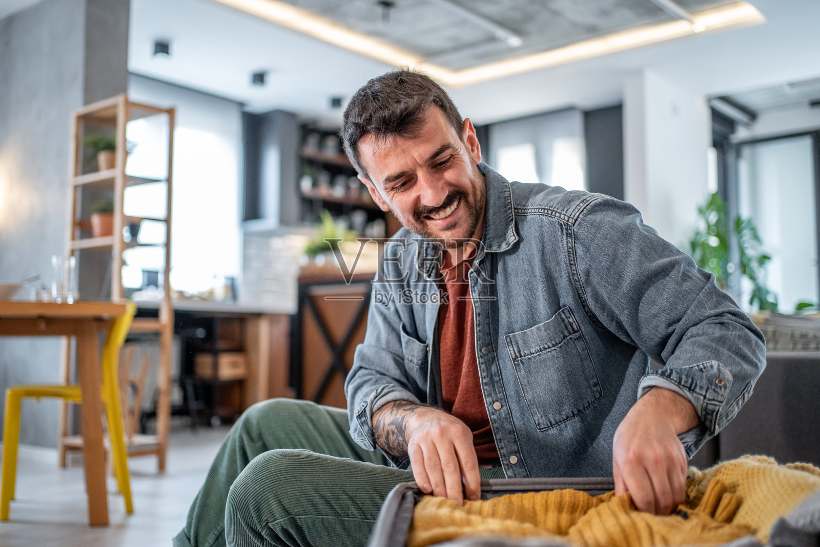 快乐的男人在家里打包旅行衣物照片摄影图片