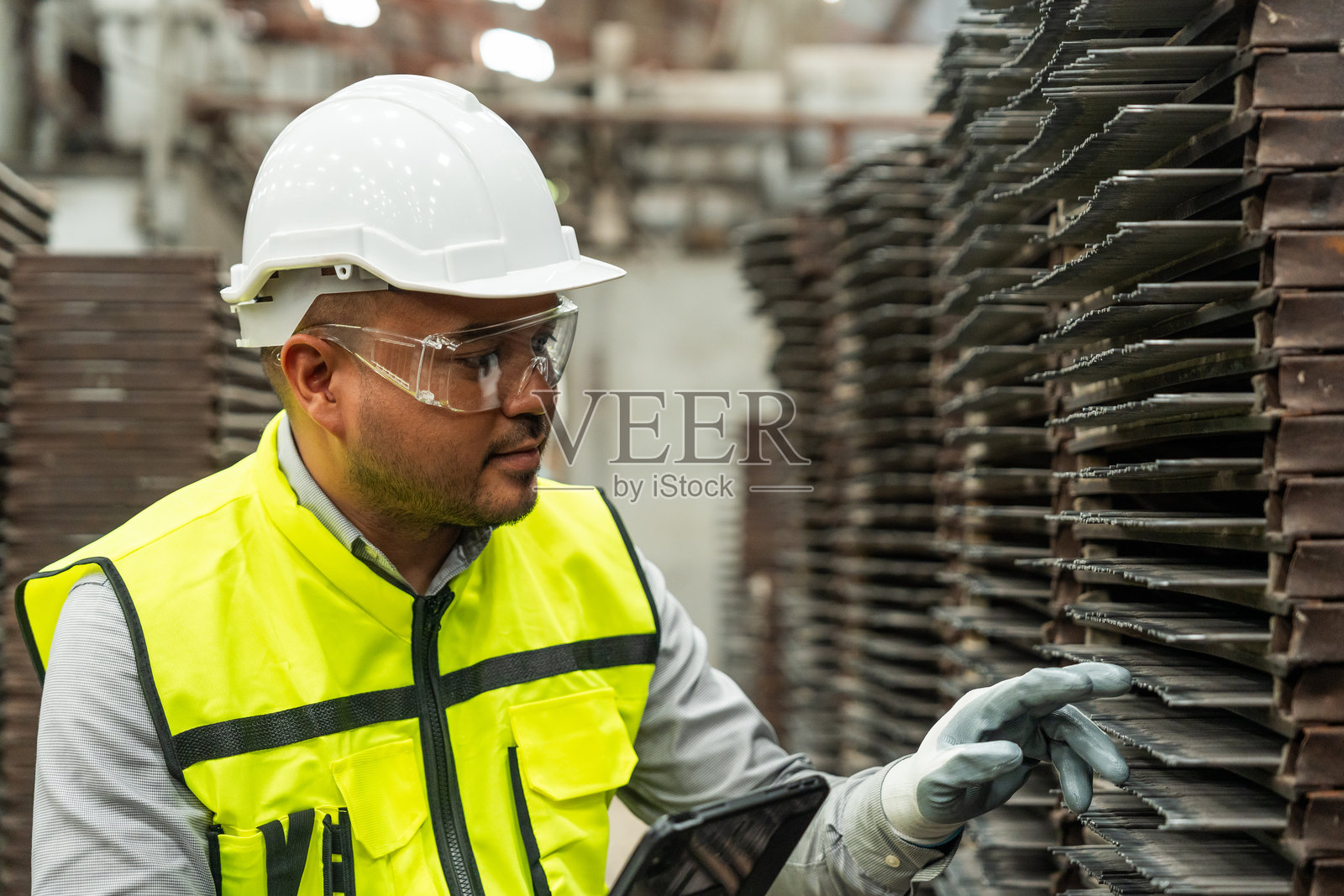 自信的工程师戴着安全头盔，手持平板电脑在工厂仓库中进行分析。亚洲技术人员在工业工厂进行设备检查和控制。照片摄影图片
