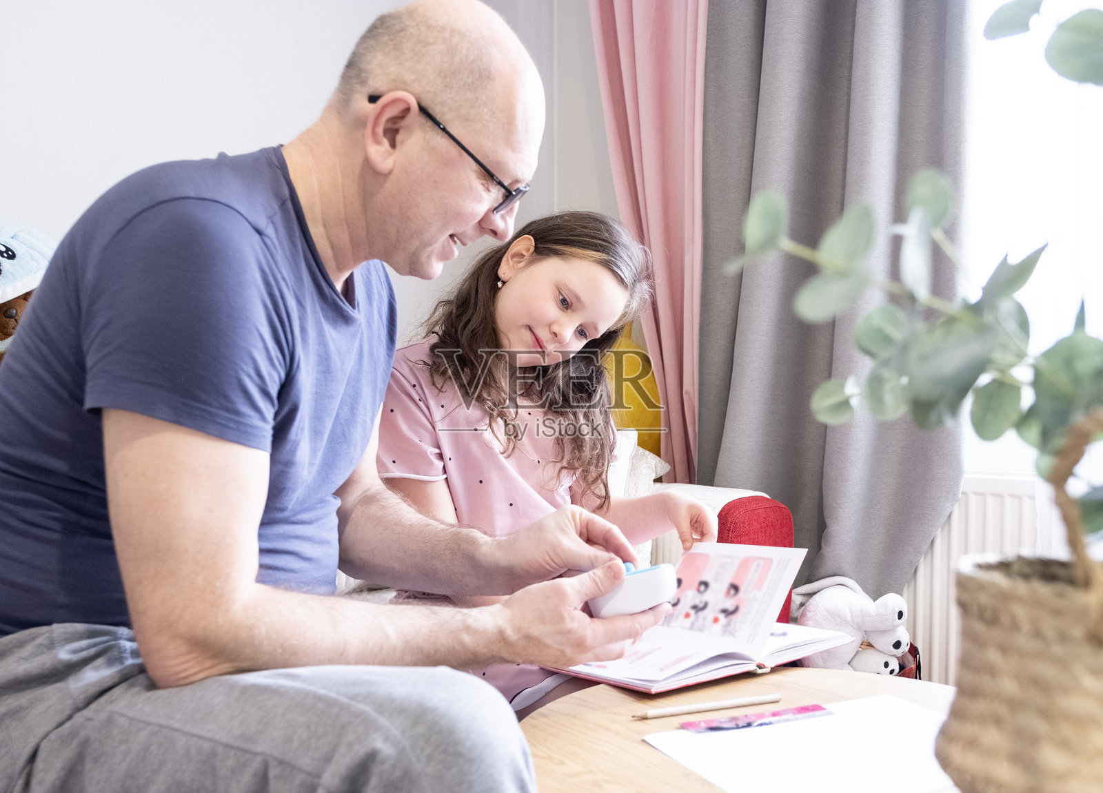10岁的白人女孩在做作业。父亲在旁边帮助，阅读教科书并解释如何完成作业。照片摄影图片