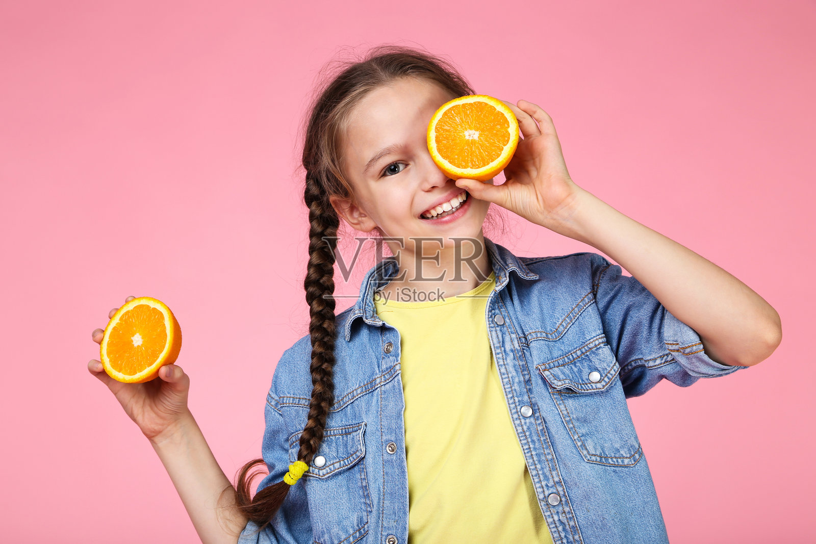 年轻女孩与橙色水果在粉色背景上照片摄影图片