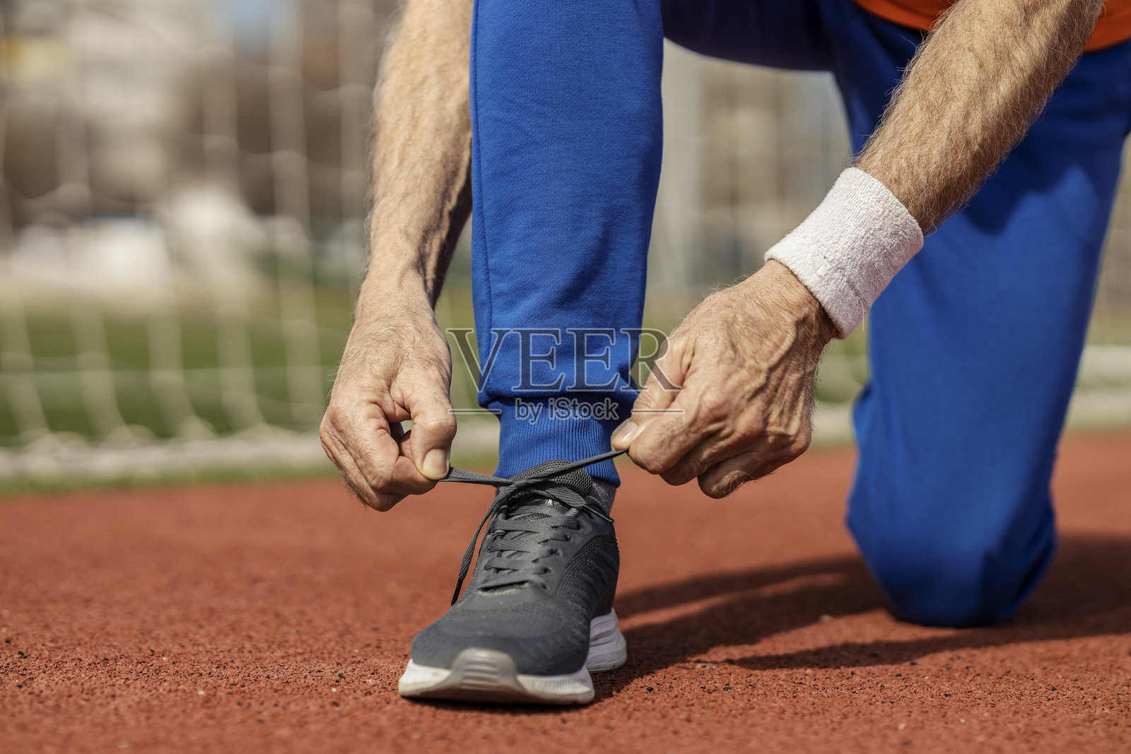 老运动员在体育场内系鞋带，准备锻炼的特写镜头。照片摄影图片