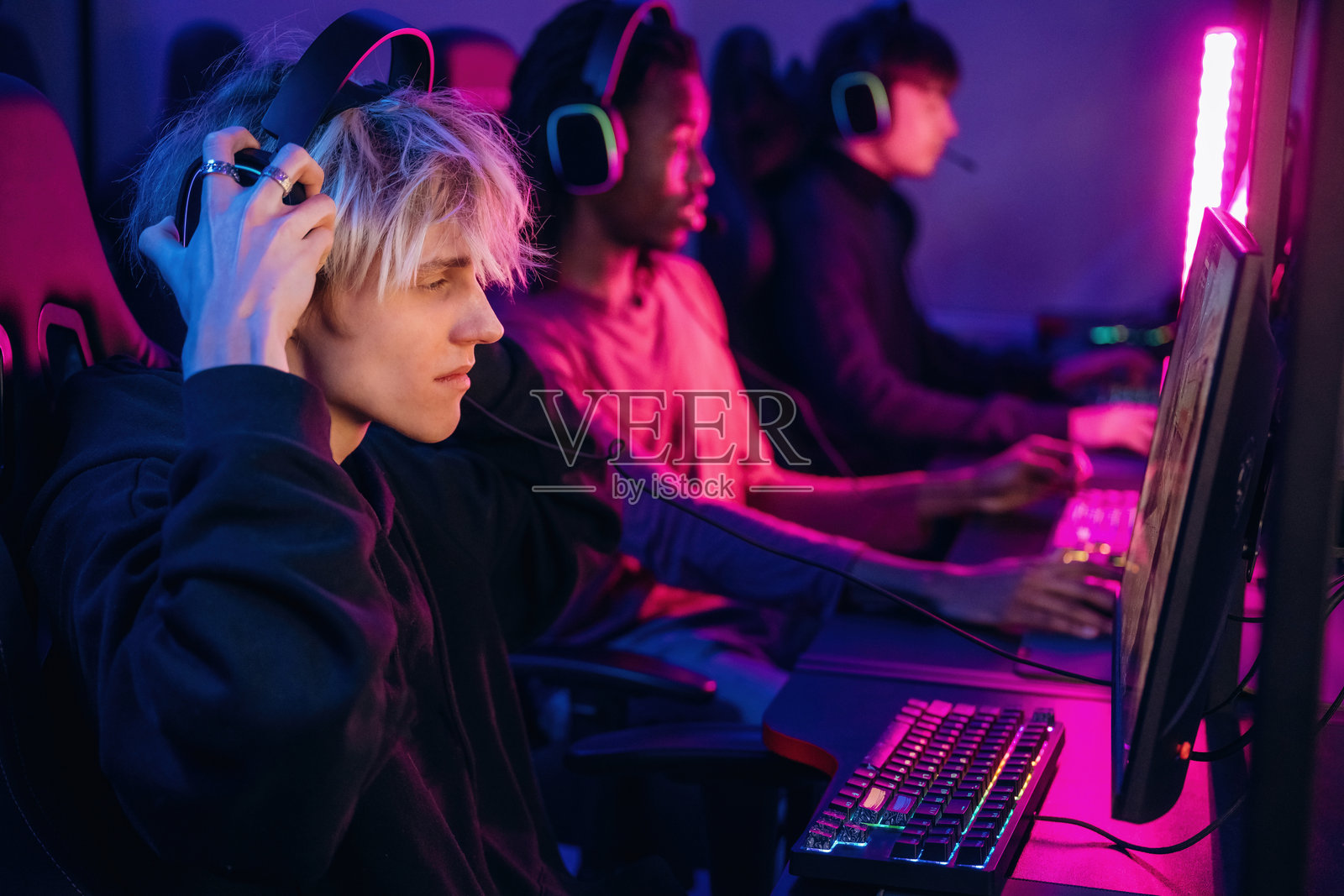 侧面视角，坐着。玩家们正在电脑前玩视频游戏。照片摄影图片