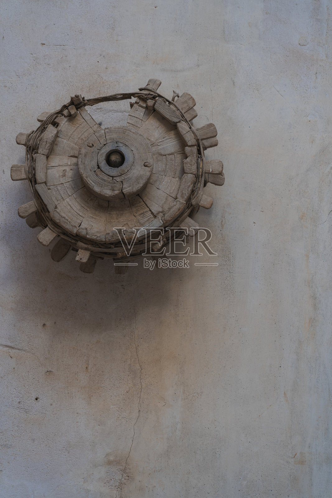 悬挂在阿曼风化墙上的旧木轮照片摄影图片