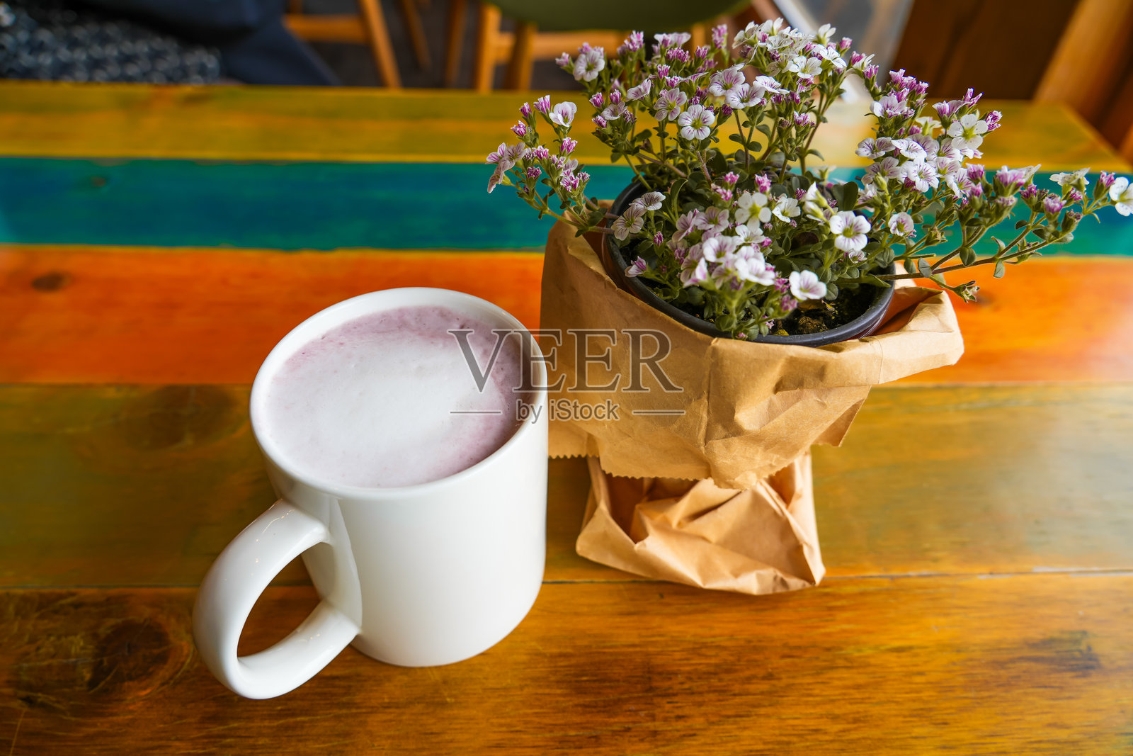 桌子上有一小盆野花和一杯甜薯拿铁。照片摄影图片