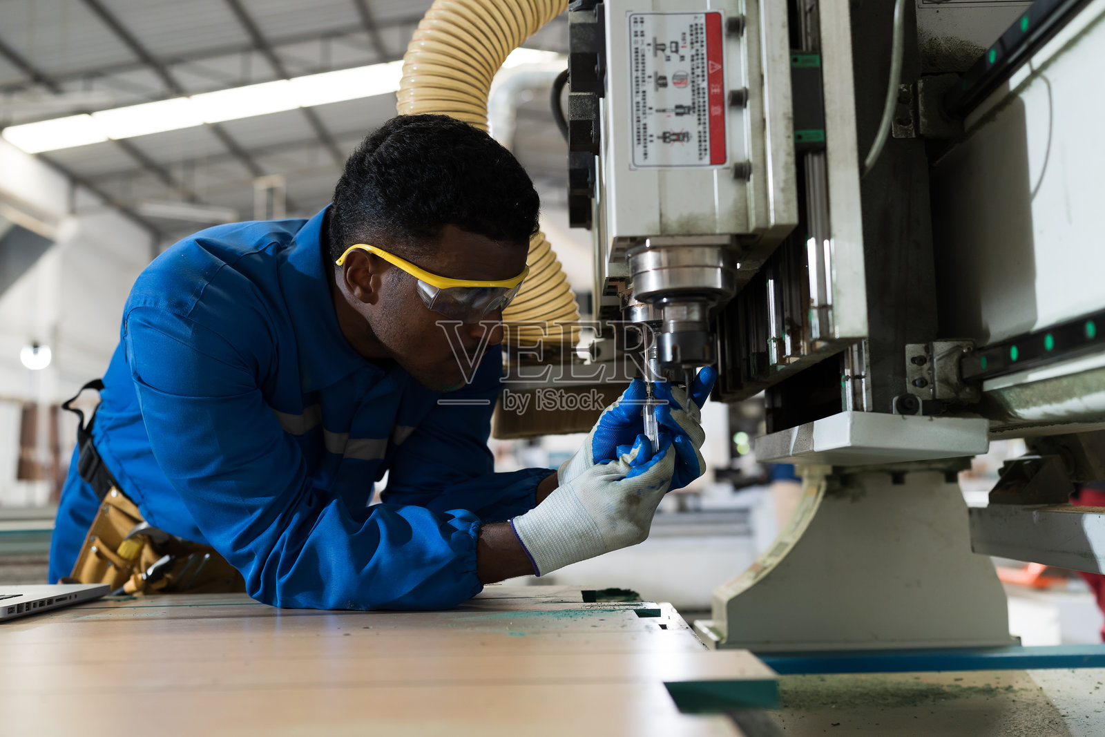 胶合板加工厂。家具制造。工程师在家具工厂维修维护数控切割机。工业制造概念照片摄影图片