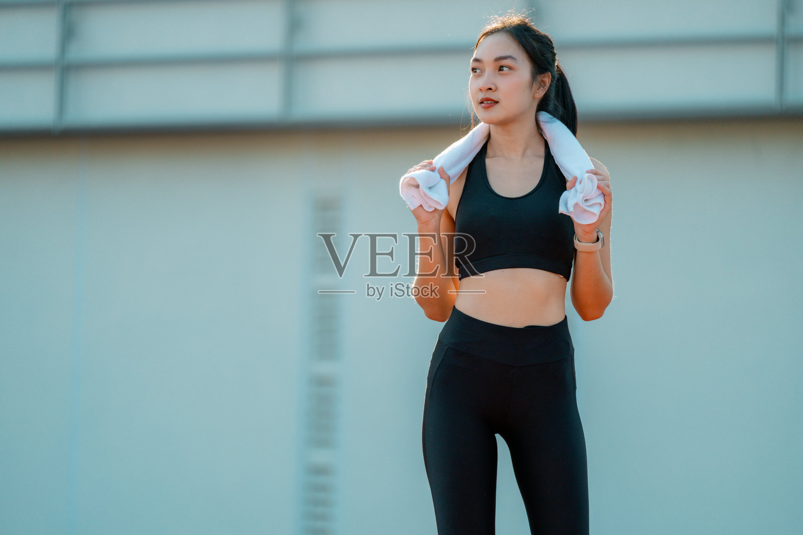 年轻的运动女性在锻炼后休息，用搭在肩上的毛巾擦汗照片摄影图片