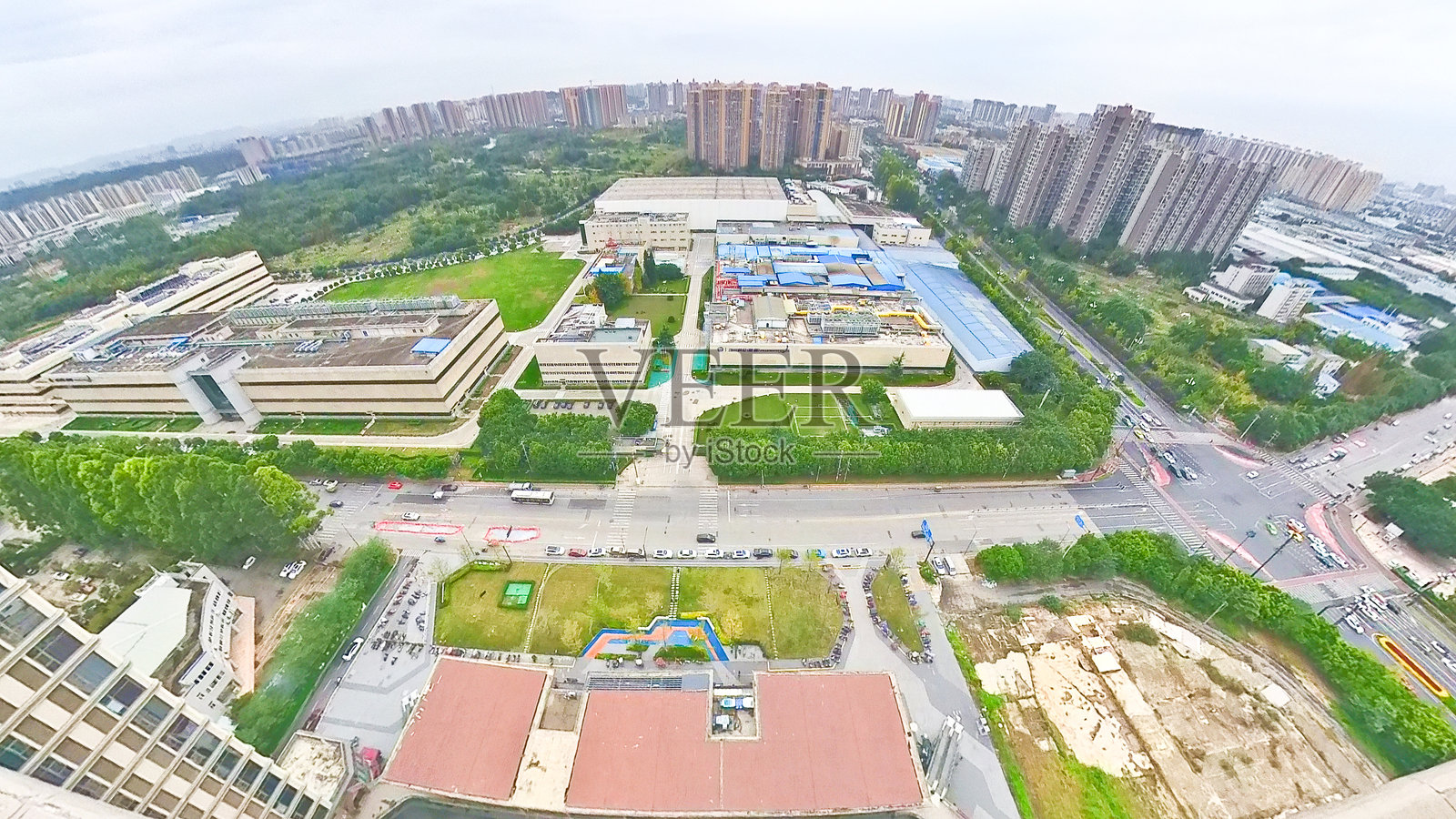 城市天际线的鸟瞰图，包含工业建筑、住宅塔楼、绿地、道路和交通，天空多云。照片摄影图片