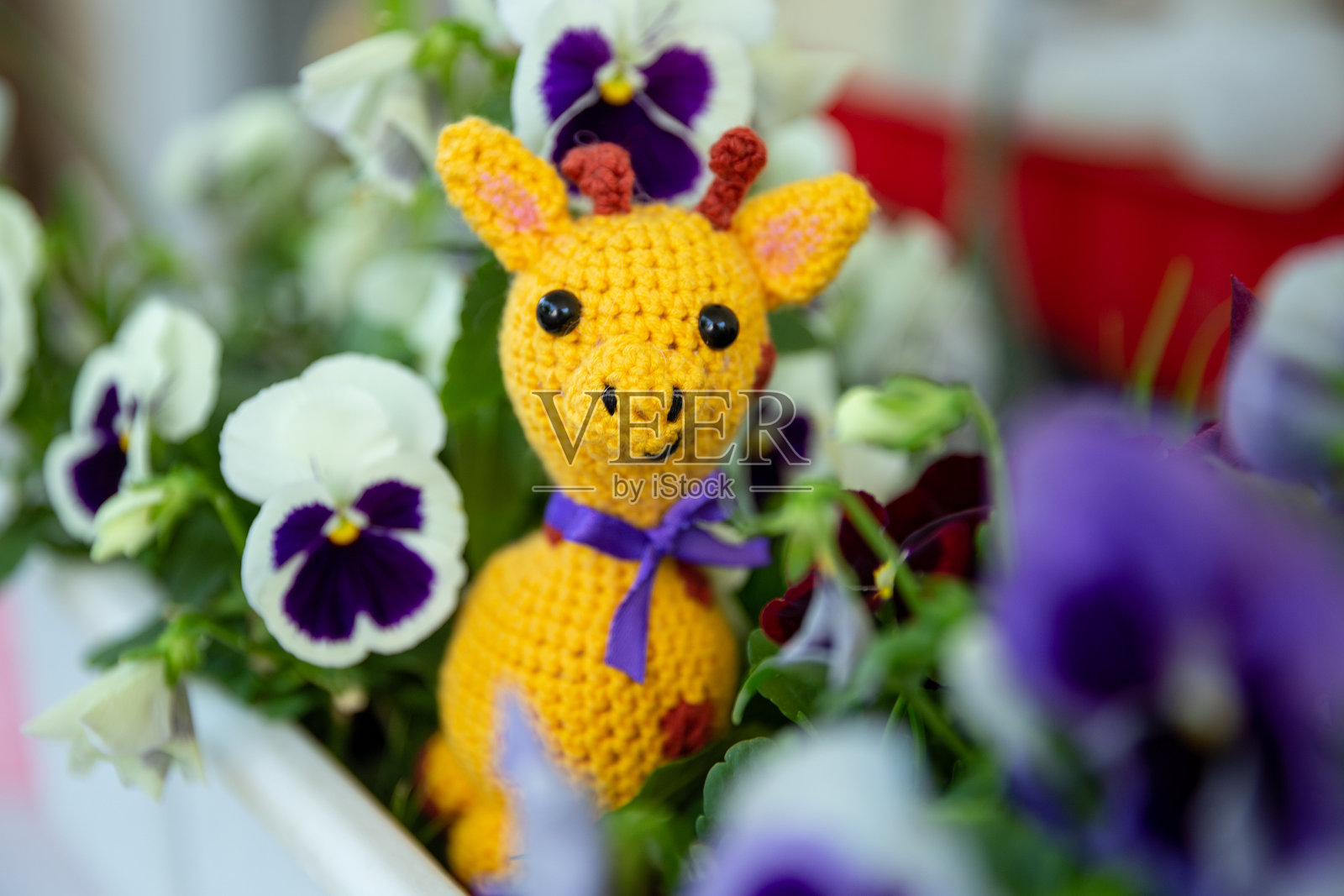 在花丛中的毛线玩具长颈鹿，手工制作，黄色长颈鹿照片摄影图片