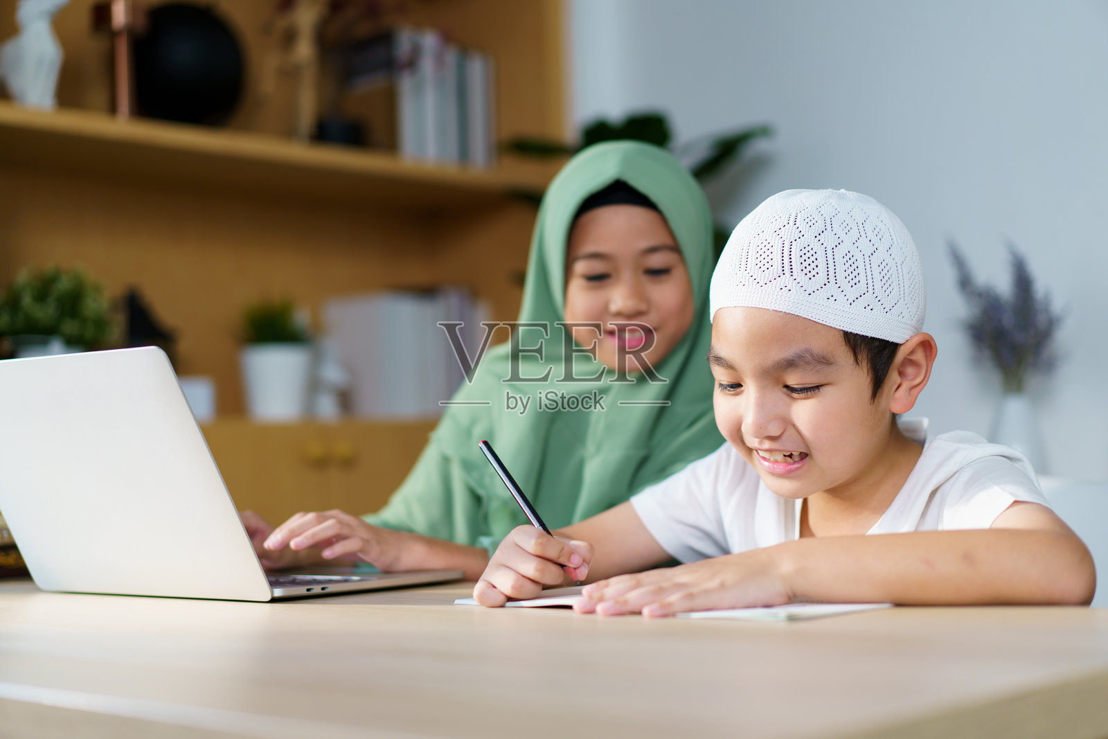 亚洲穆斯林兄妹在家学习和做作业。照片摄影图片