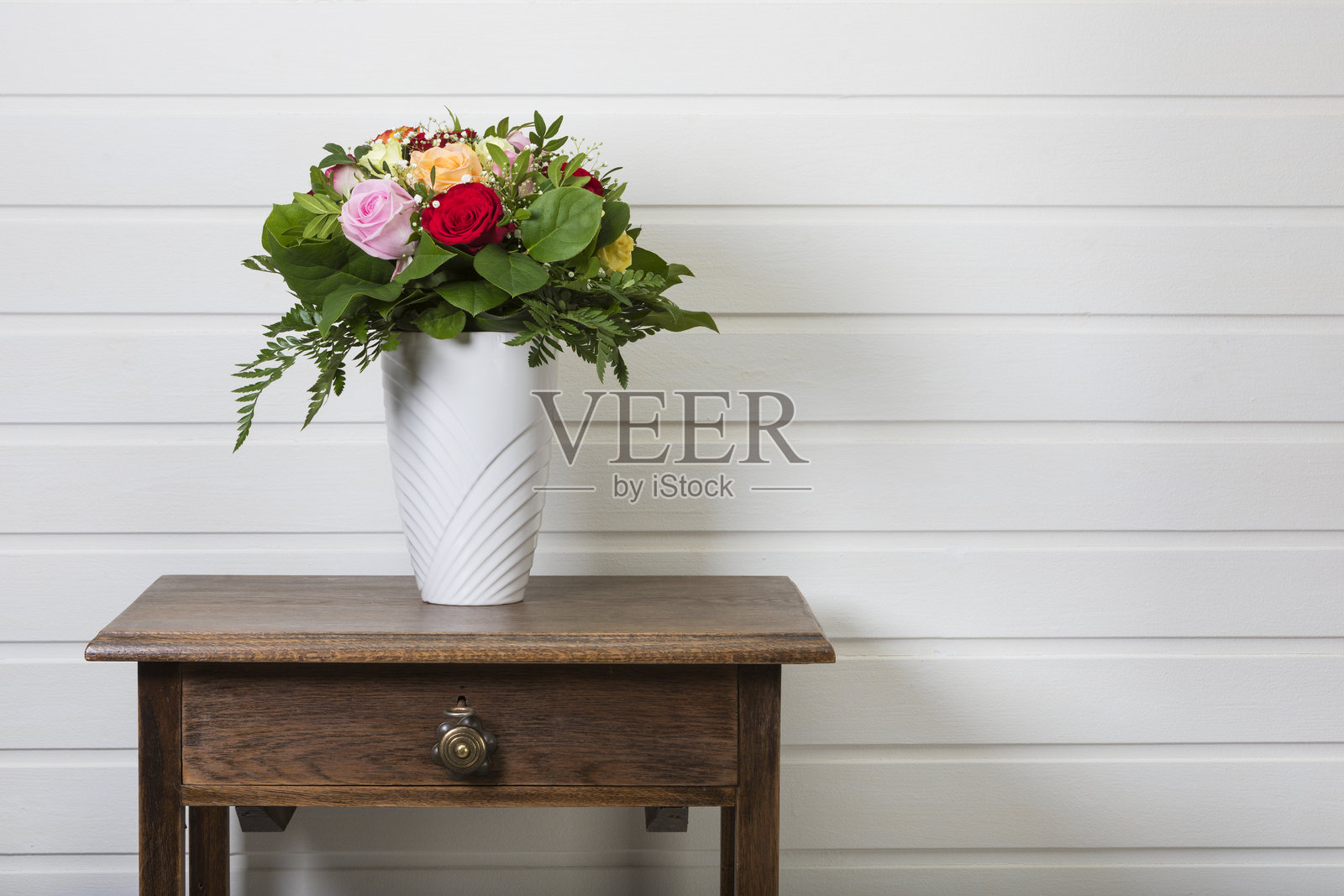 侧桌上的花瓶里插满了各种玫瑰的花束照片摄影图片