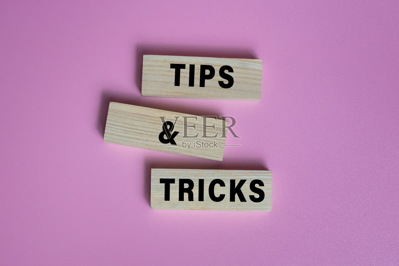 粉色背景上孤立的木块上的提示和技巧字词照片摄影图片