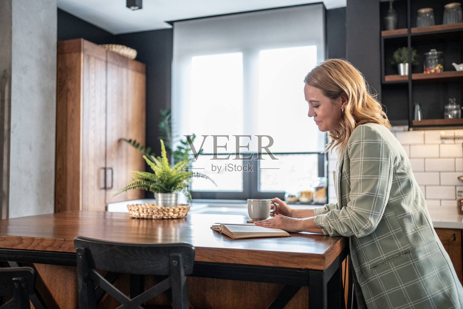 女商人在现代厨房中享受书籍和咖啡照片摄影图片