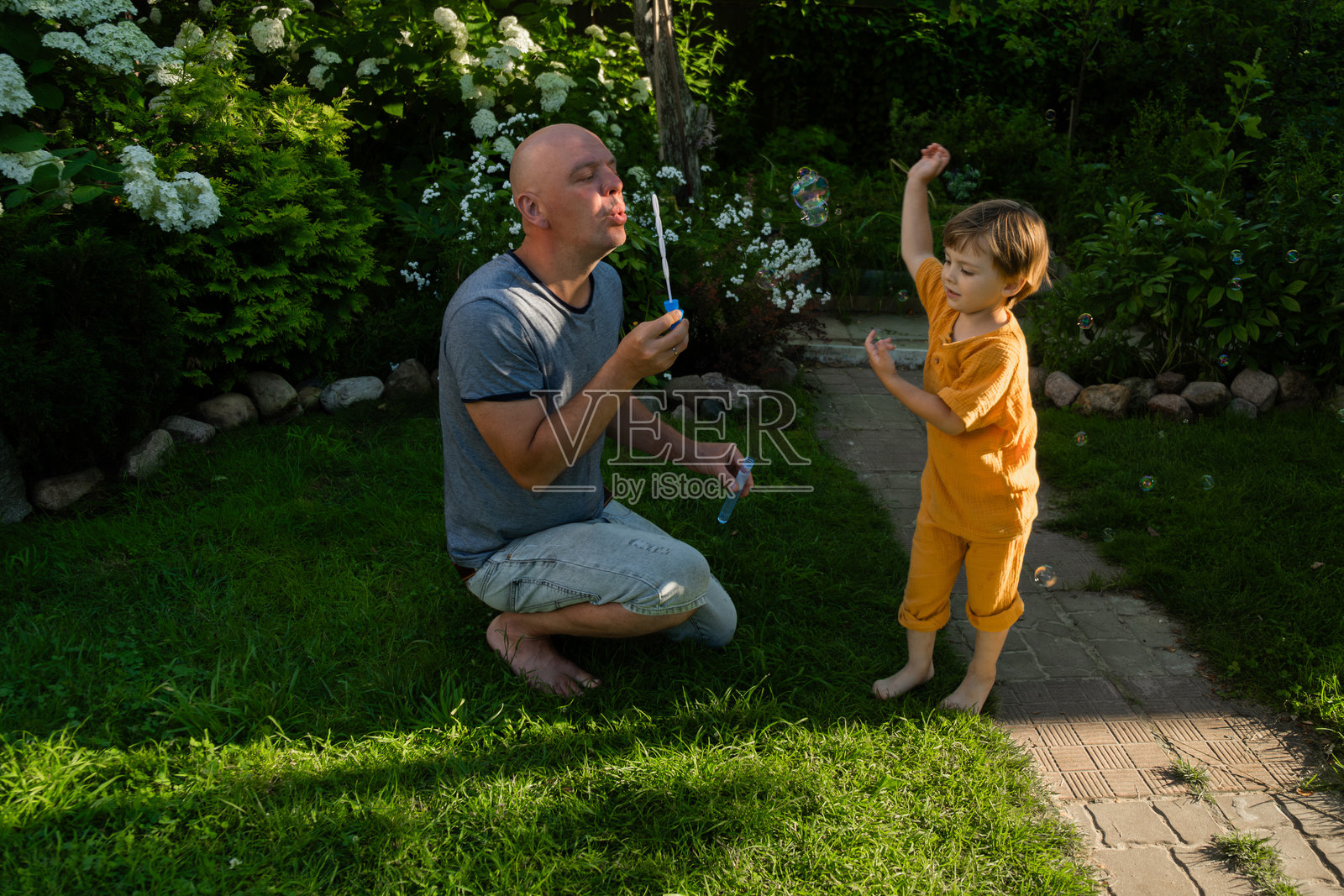父亲和儿子在夏天的草坪上快乐地吹泡泡照片摄影图片